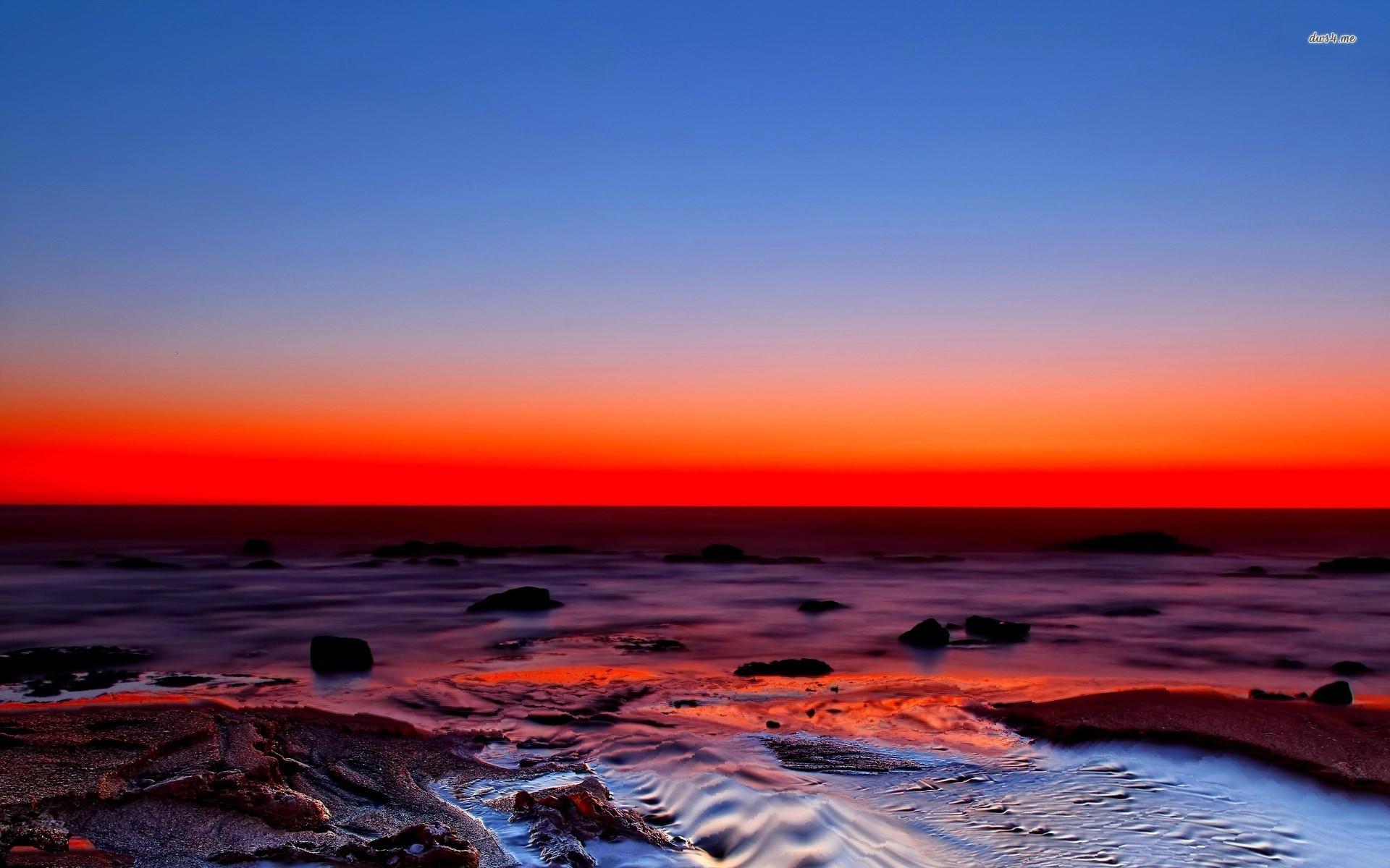 Amazing red sunset over the rocky beach wallpaper