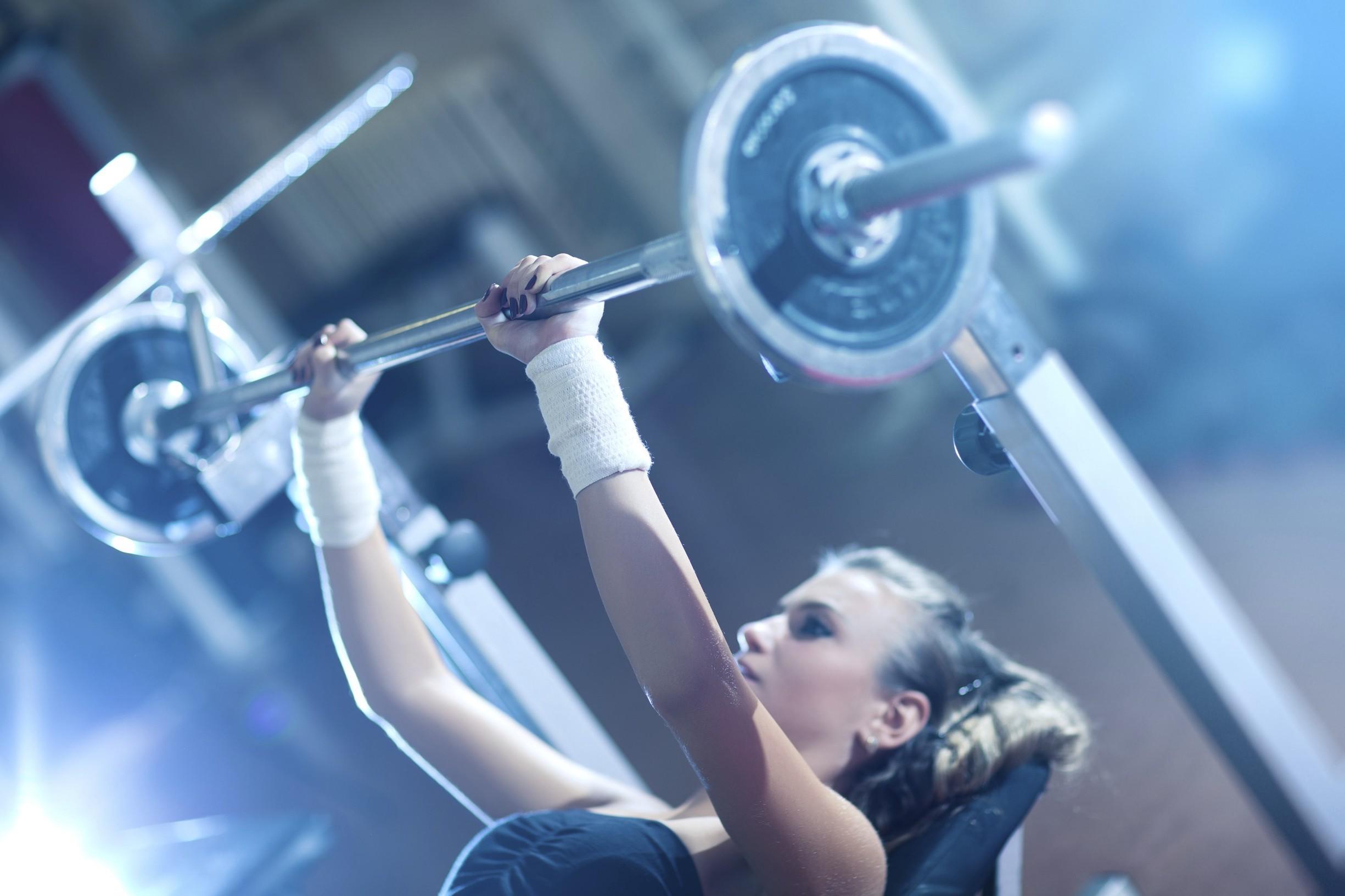A Woman Lifting Weights Doing Bench Press In The Gym Health