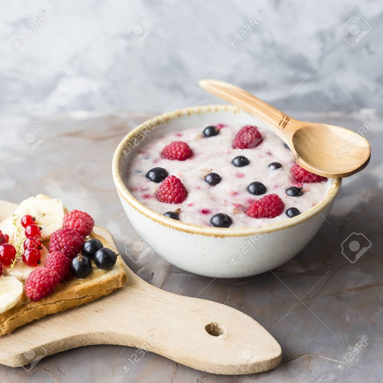 Best A bowl of oatmeal with berries next to a board