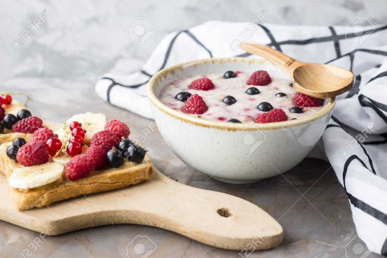 Best A bowl of oatmeal with berries next to a board