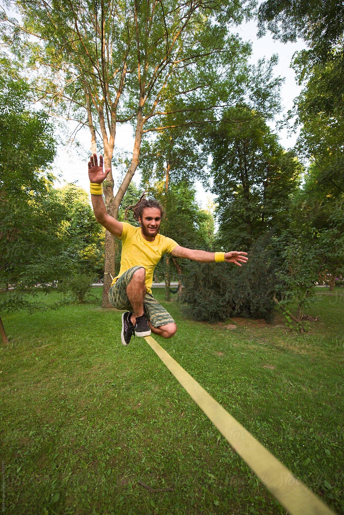 Hipster doing tricks on a slackline in the park by RG&B