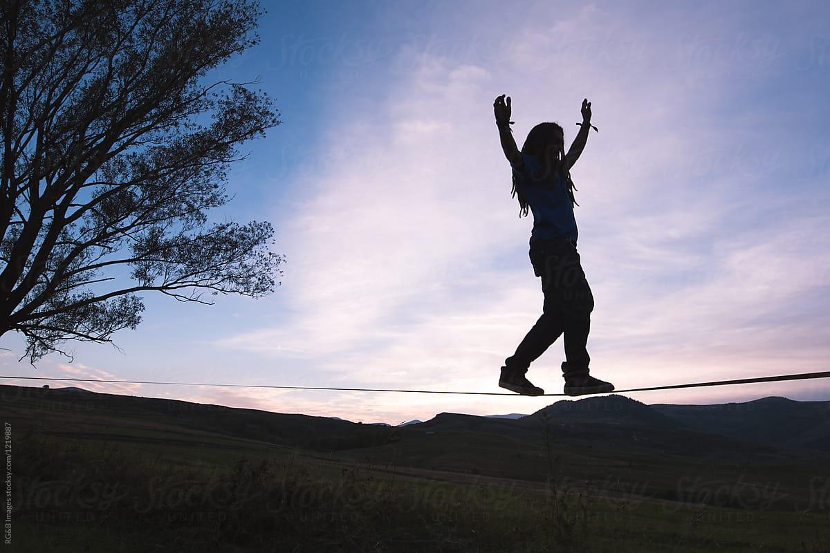 Man's silhouette stepping on slackline outdoor in