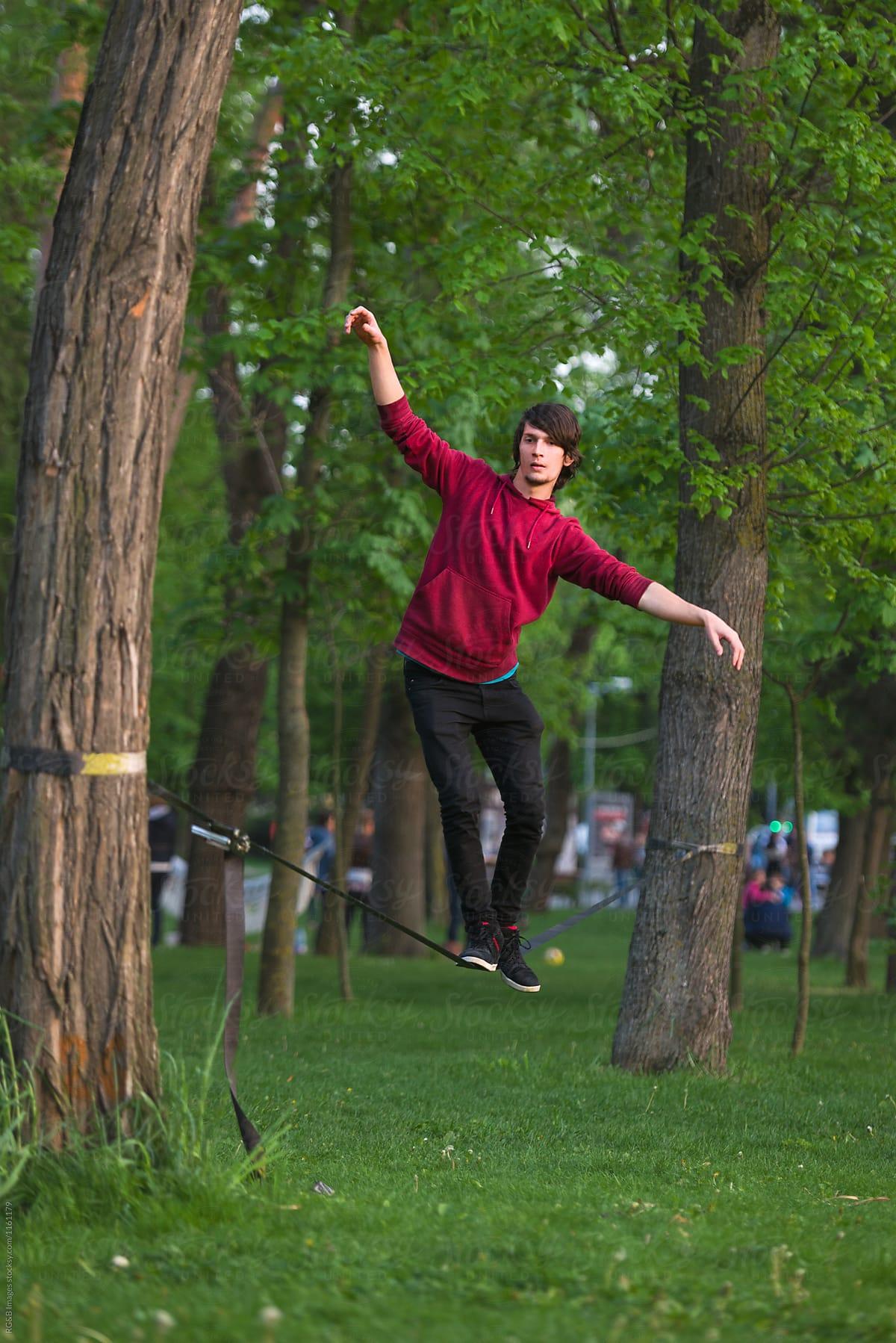 Young man keeping his balance on a slackline between trees