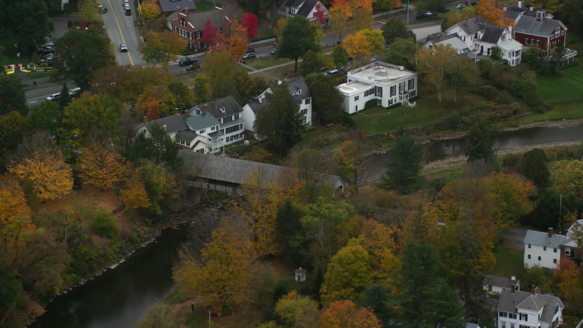 6K stock footage aerial video orbiting a small covered bridge, Ottauquechee River, autumn, Woodstock, Vermont Aerial Stock Footage AX151_020. Axiom