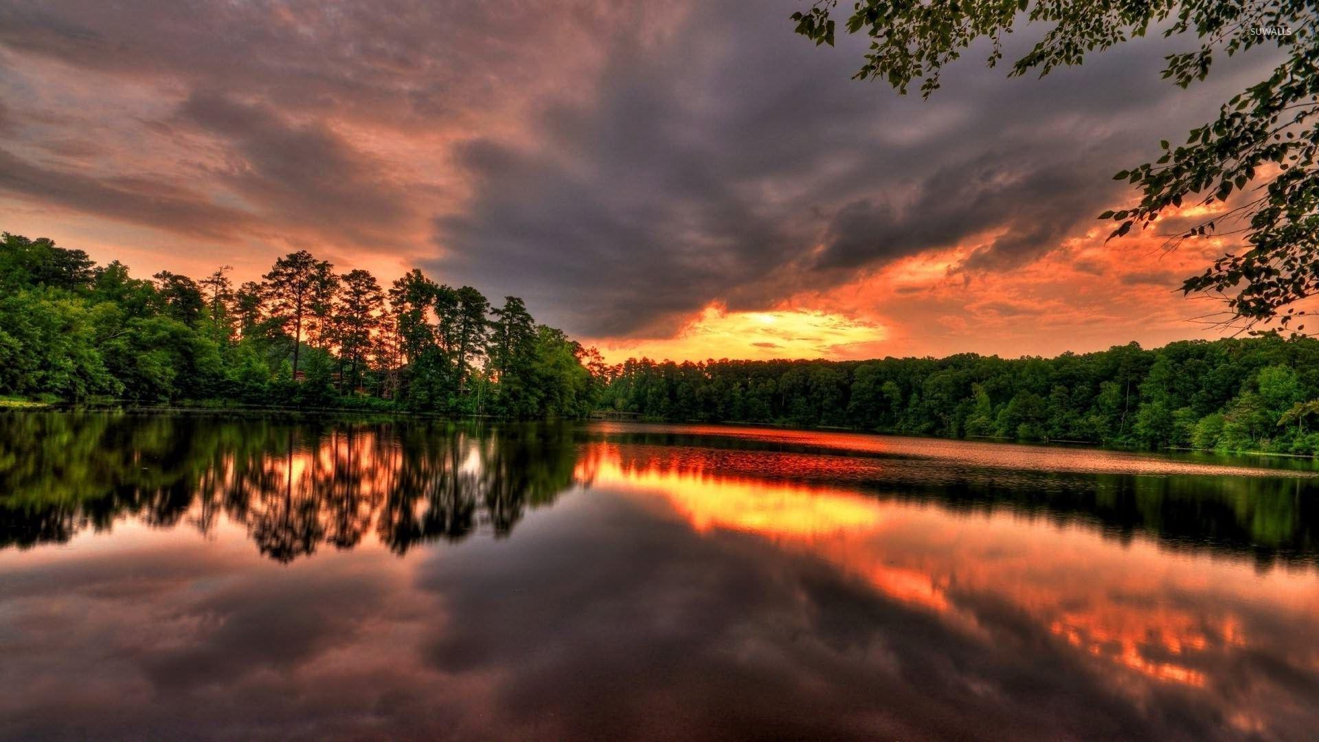 Golden sunset reaching through dark clouds reflecting in