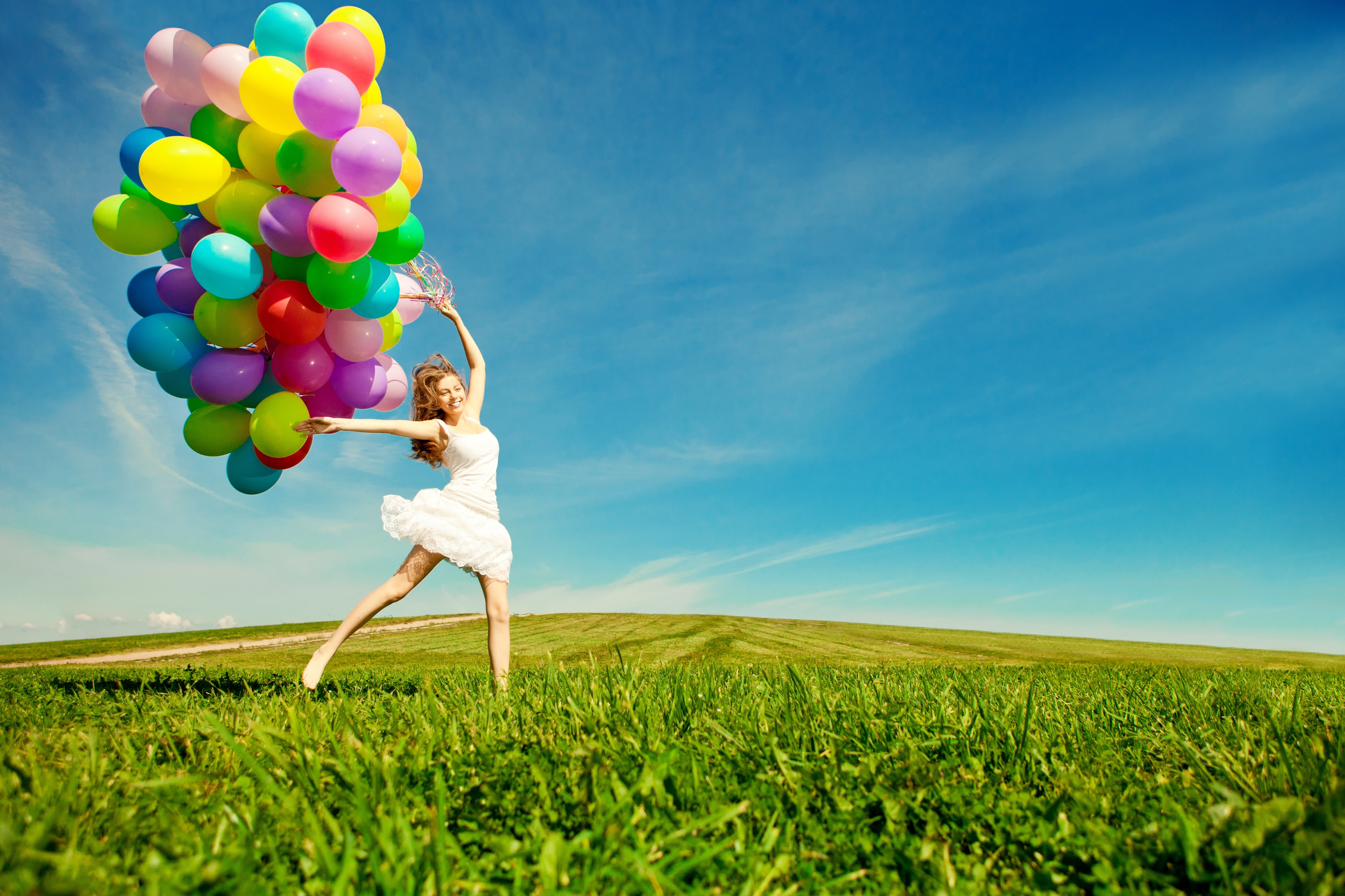 Woman Jumps On Green Grass Holds Assorted Color Balloons