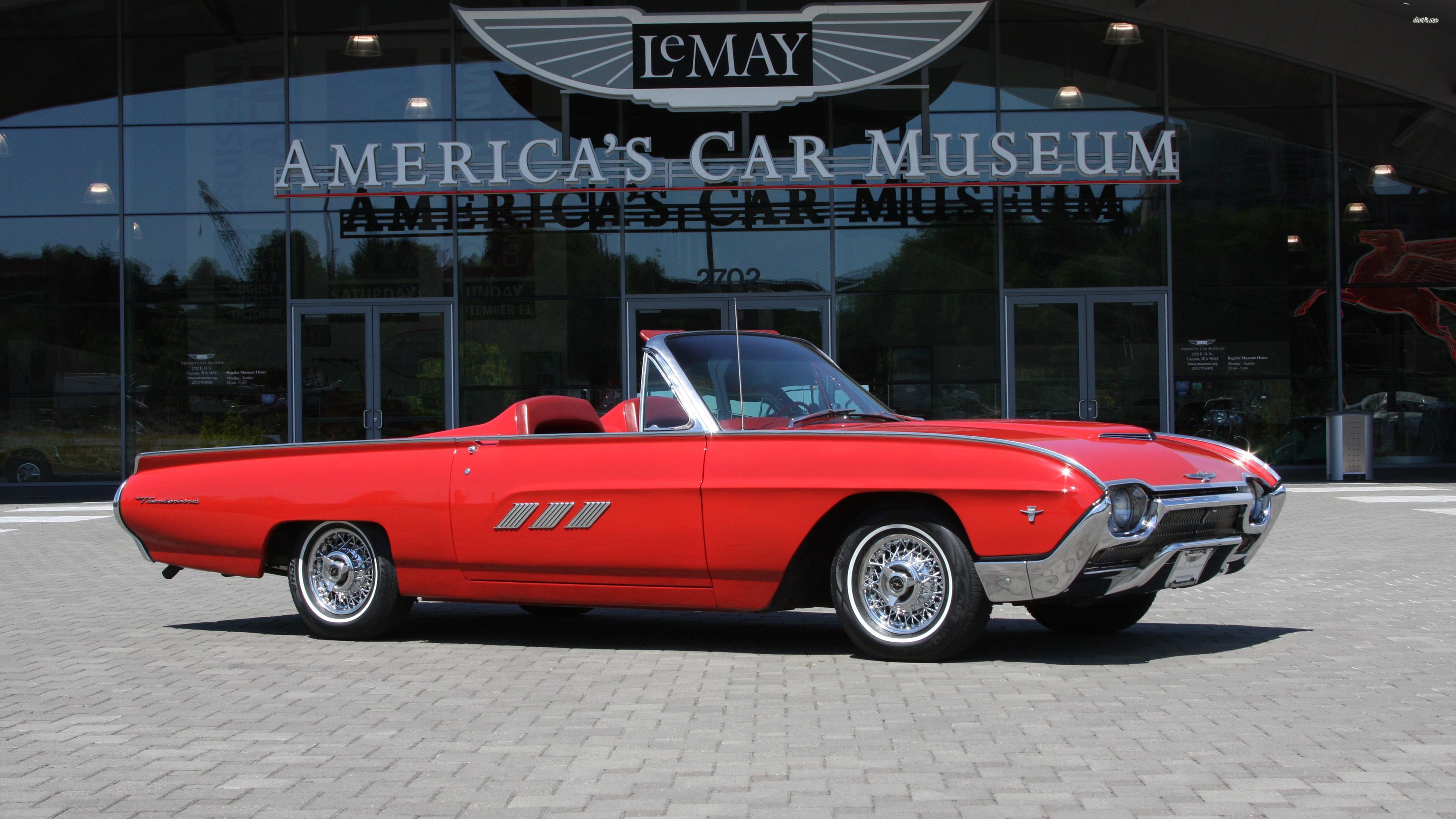 Red Ford Thunderbird in front of a car museum wallpaper