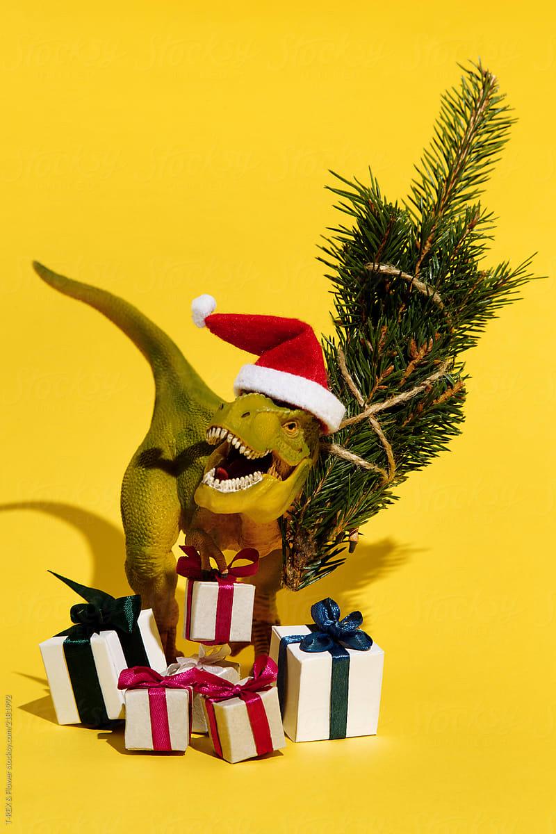 Decorative dinosaur in Christmas hat holding fir