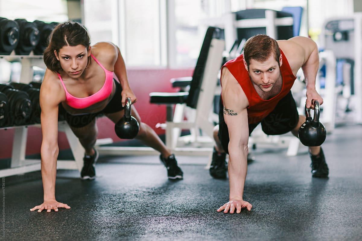 Couple working out together doing pushup row with kettlebell