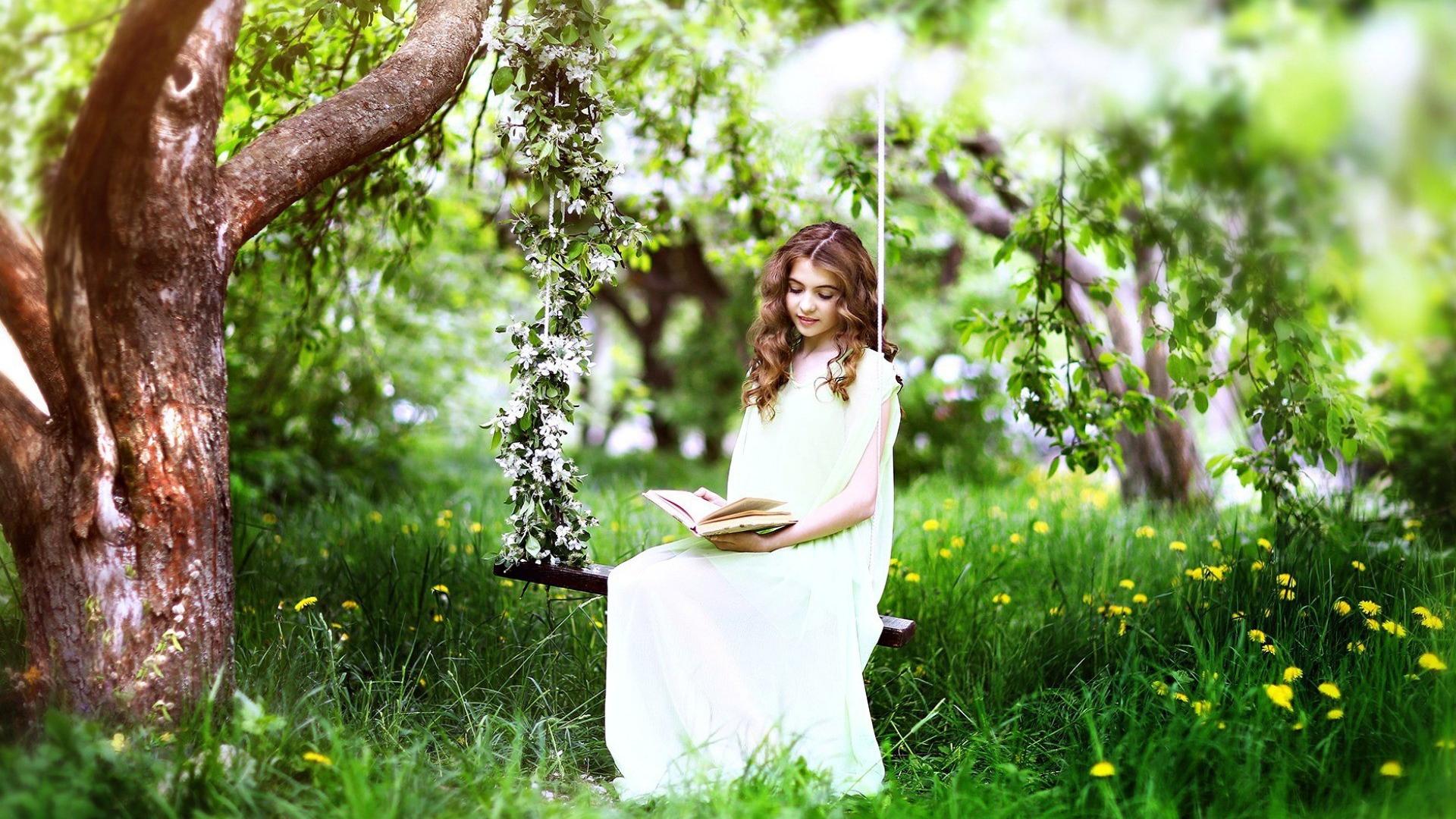 Girl sitting on a swing and reading a book Desktop