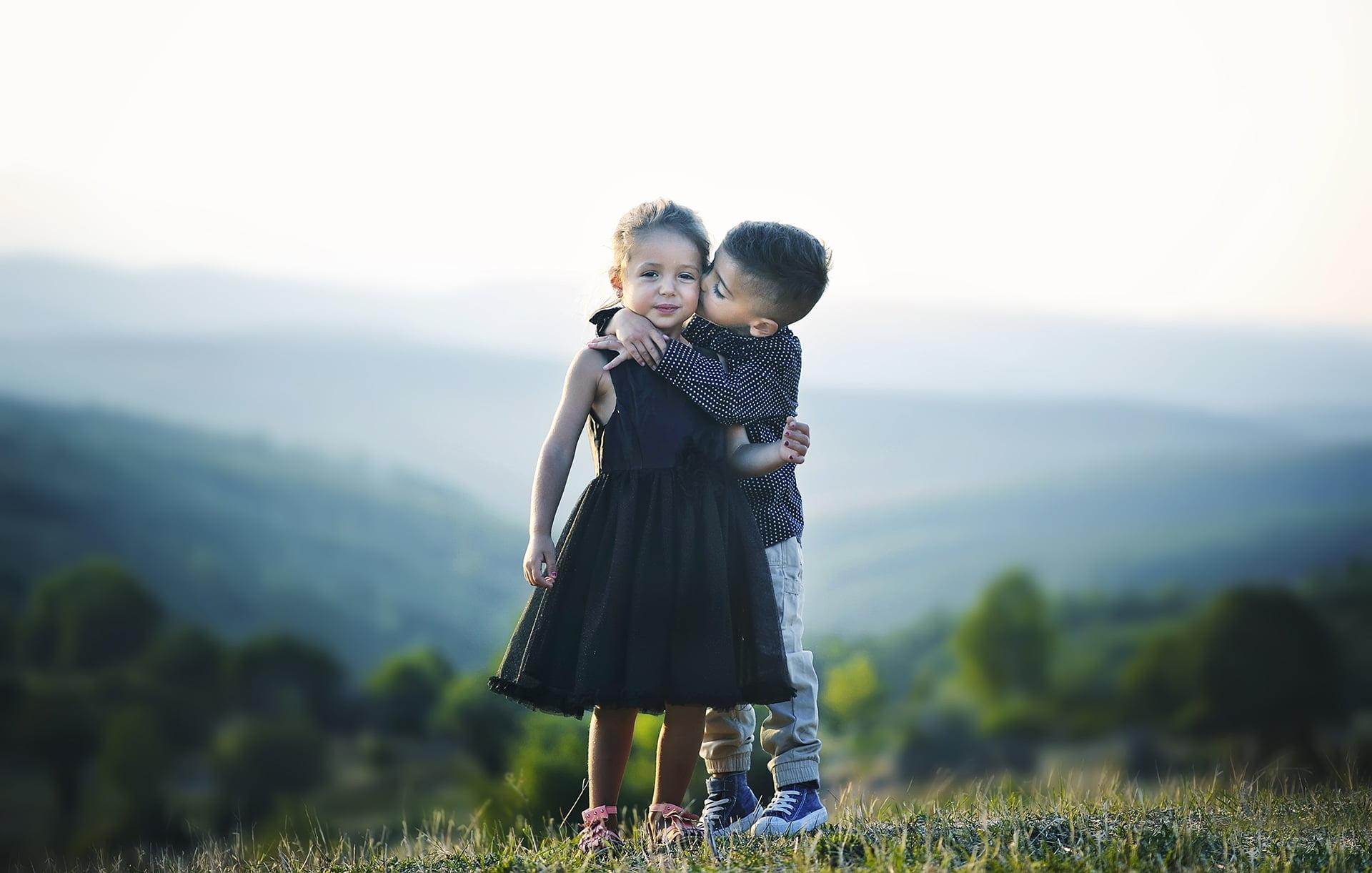 Selective focus photography of boy kissing and hugging girl