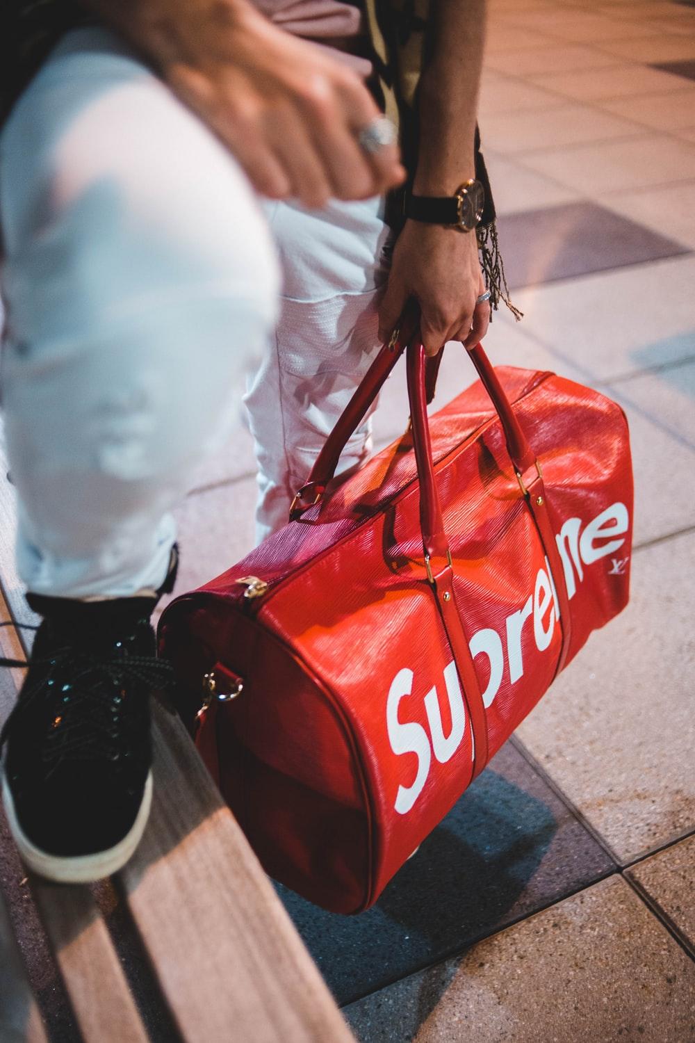 person holding red Supreme bag photo