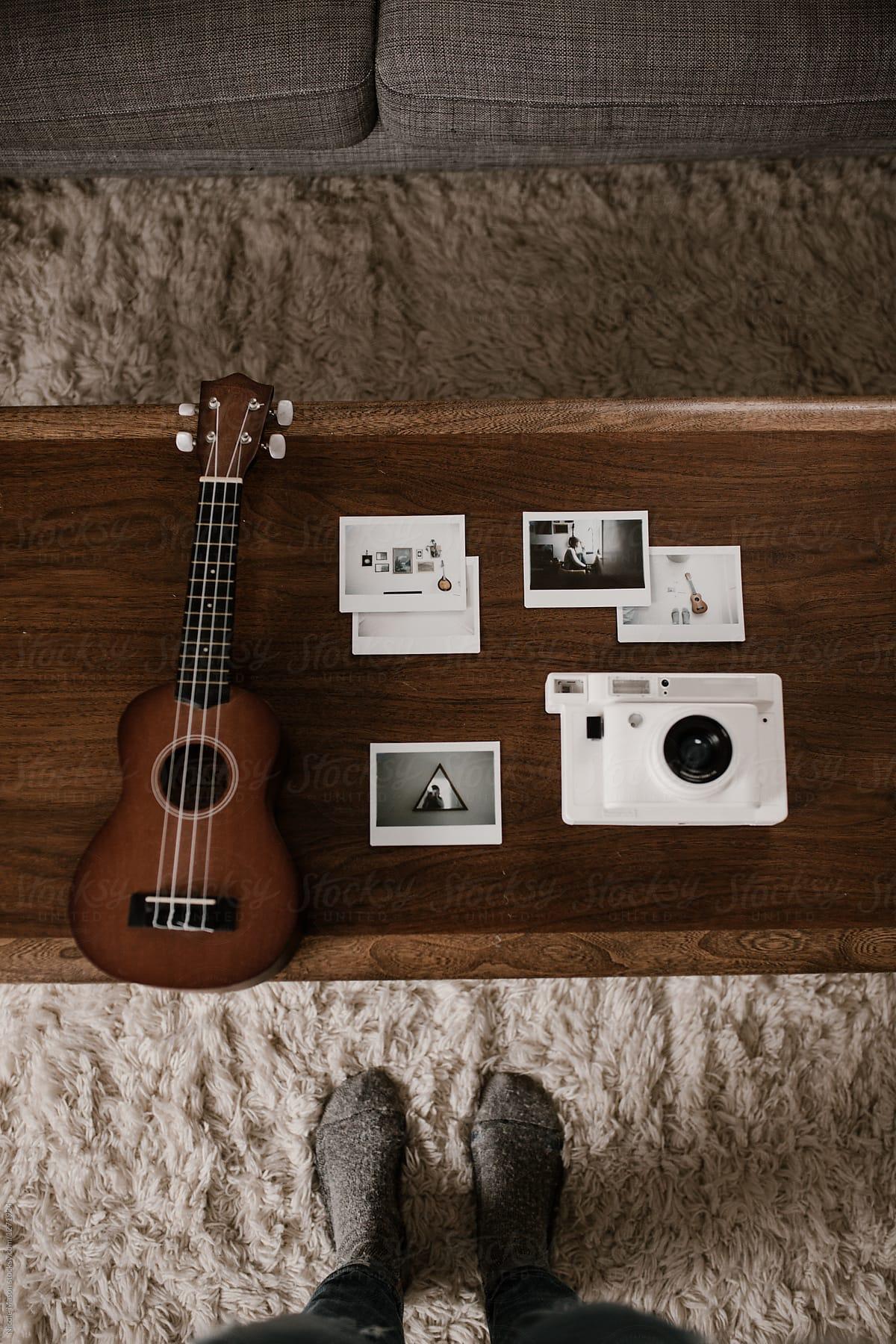 camera, photo and ukulele arranged on coffee table in cozy