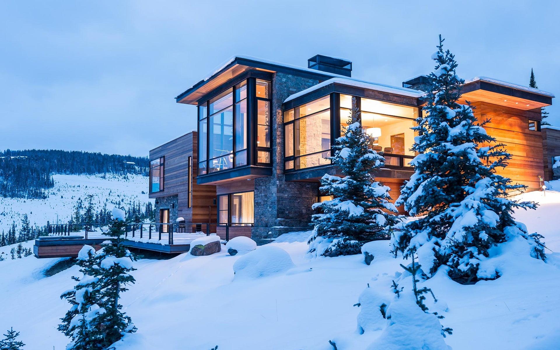 Brown wooden cabin up on snow mountain under blue sky at