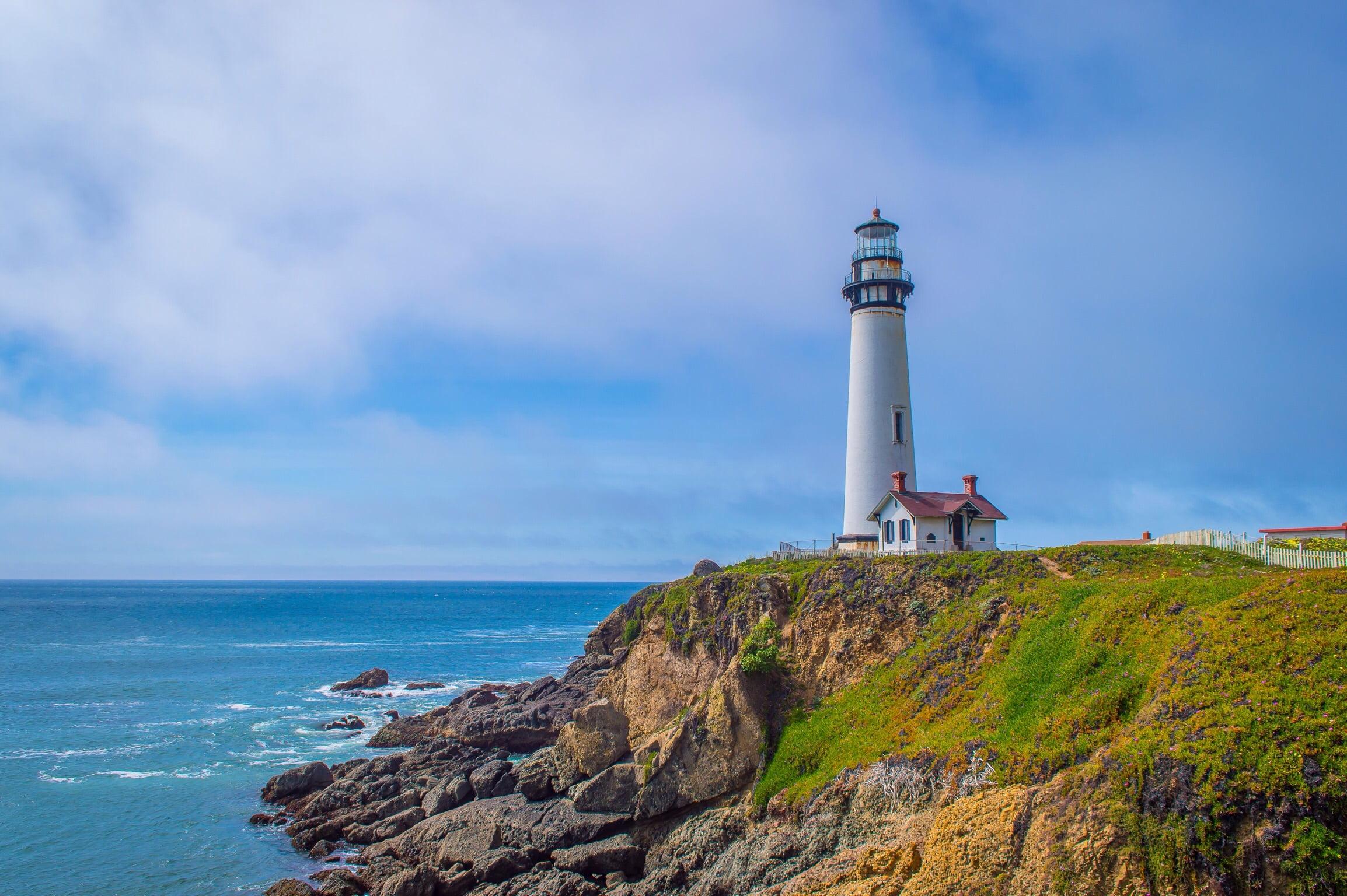 Photography of white lighthouse near mountain beside