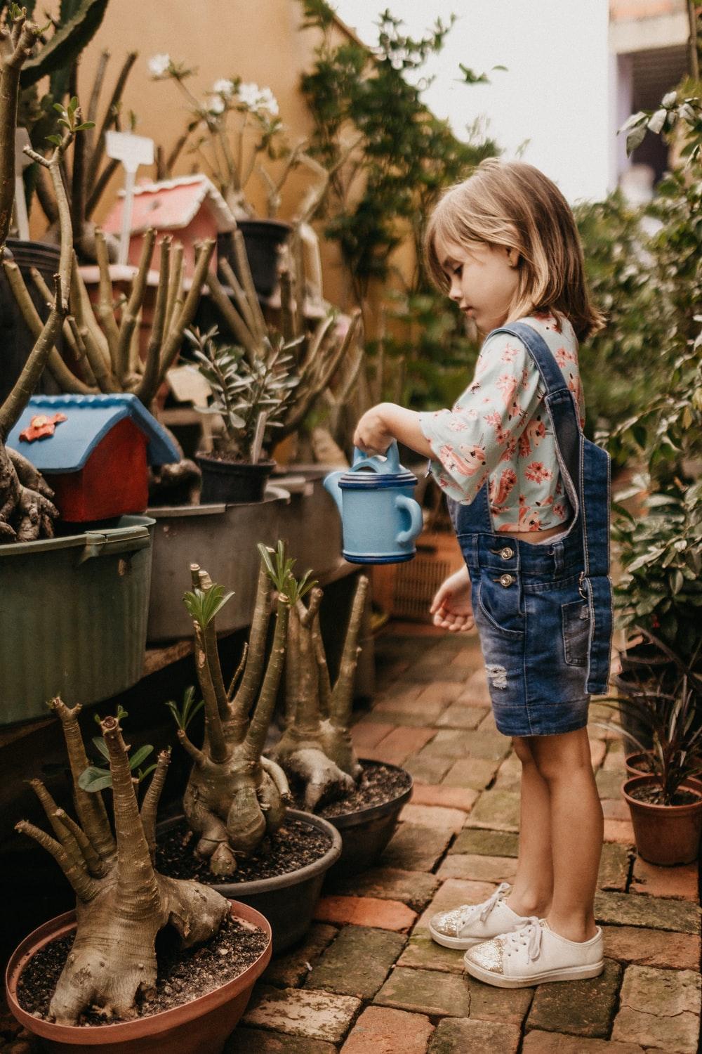 girl wearing blue romper holding teal watering can photo