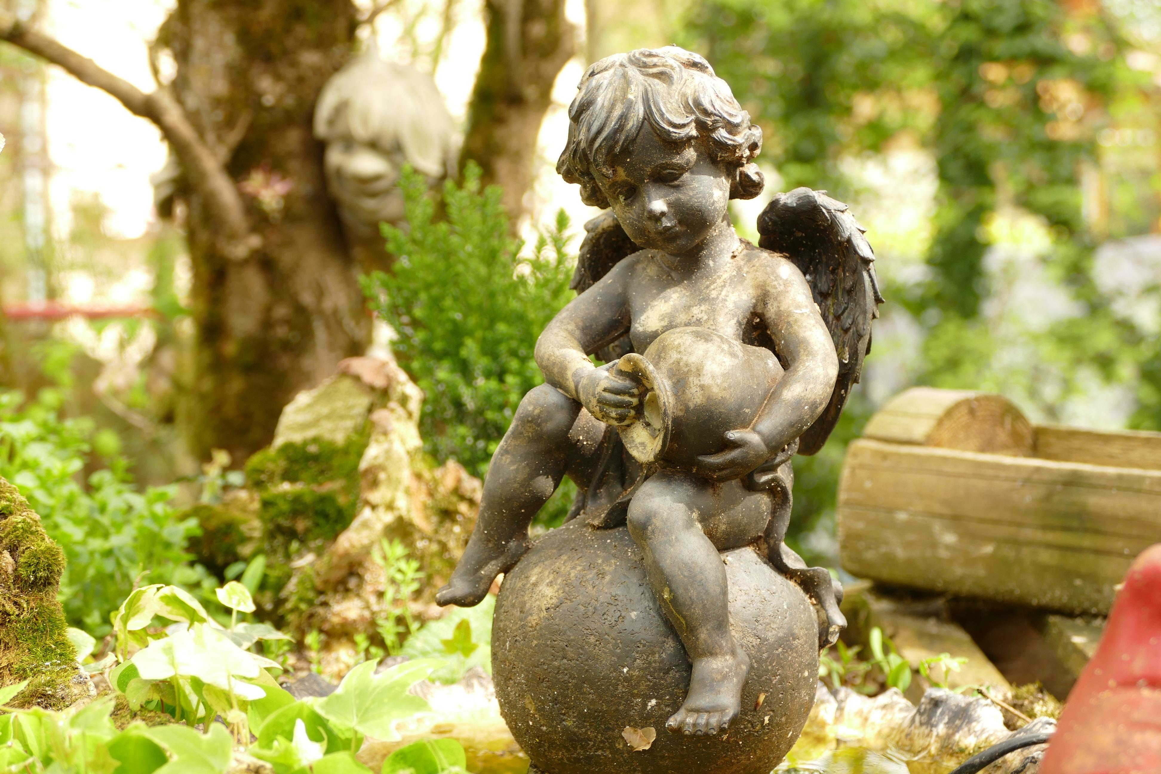 A cherub statue in a garden 4k Ultra HD Wallpaper