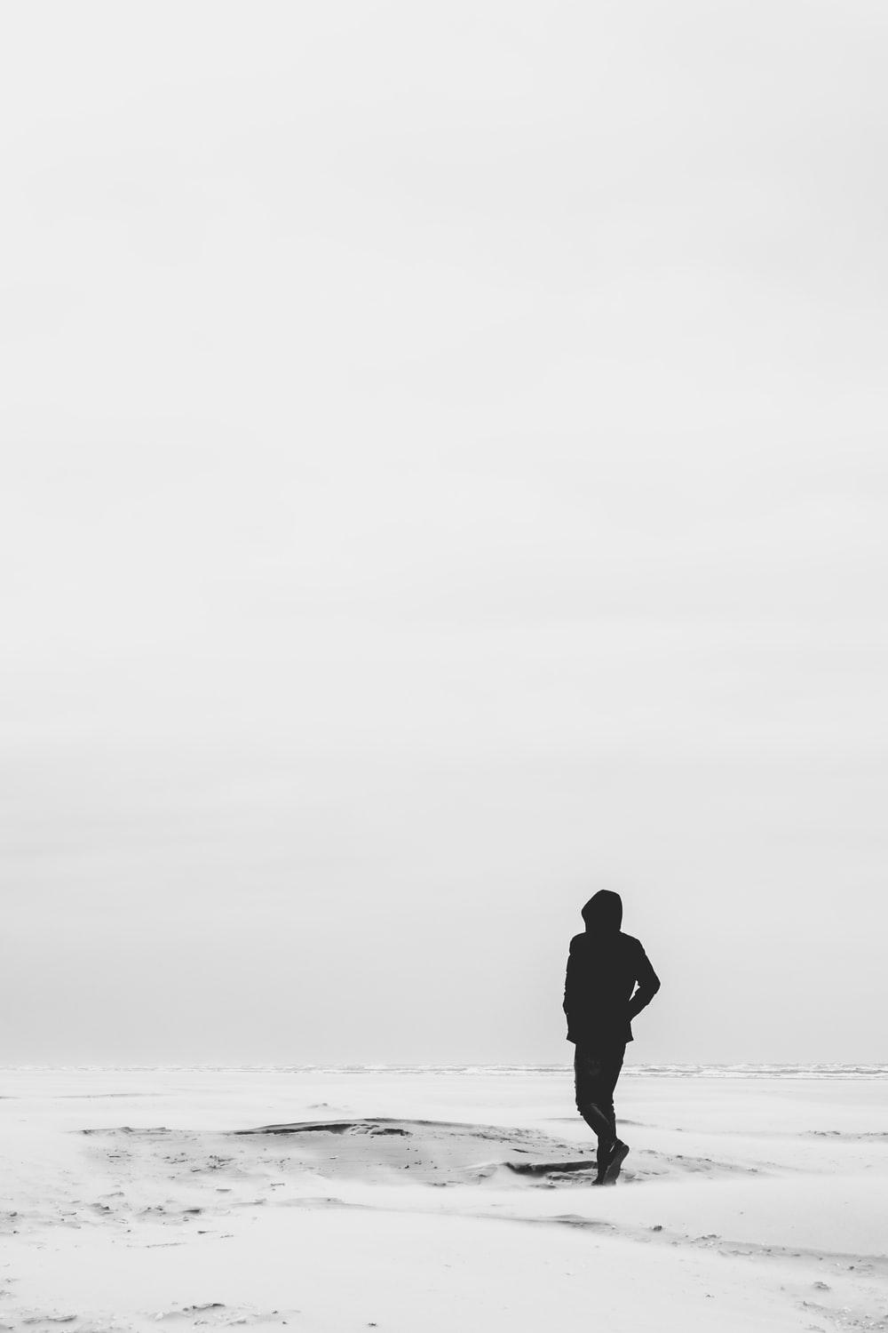 man wearing hoodie standing on snow covered field during
