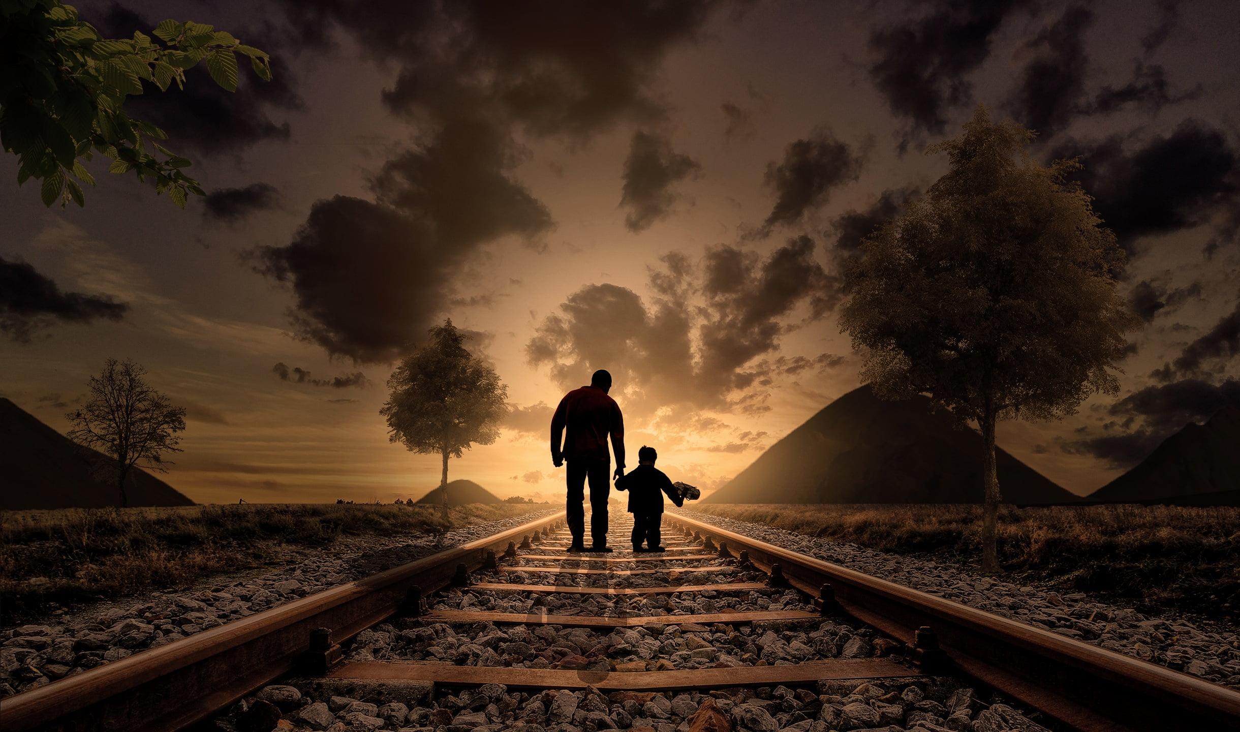 Silhouette of man and boy walking on the railway HD