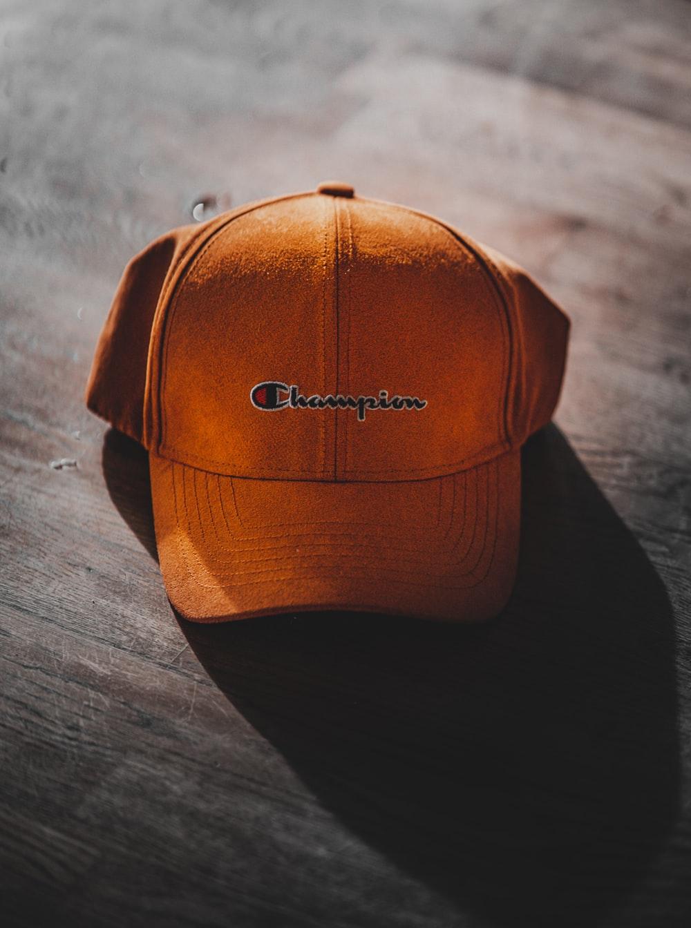 orange Champion curve brimmed cap on gray surface photo
