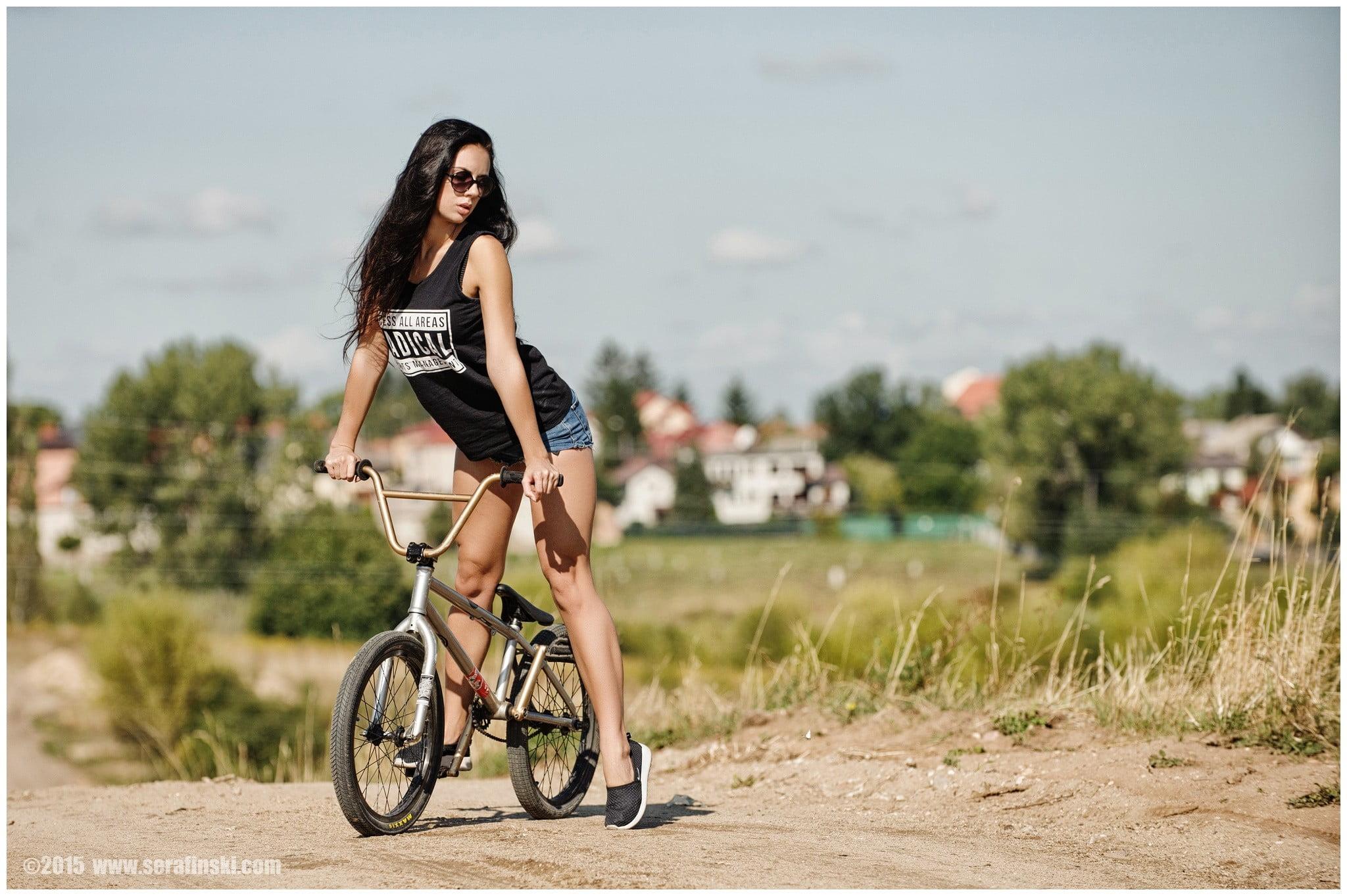 Woman wearing black tank top and blue short shorts ride on gray