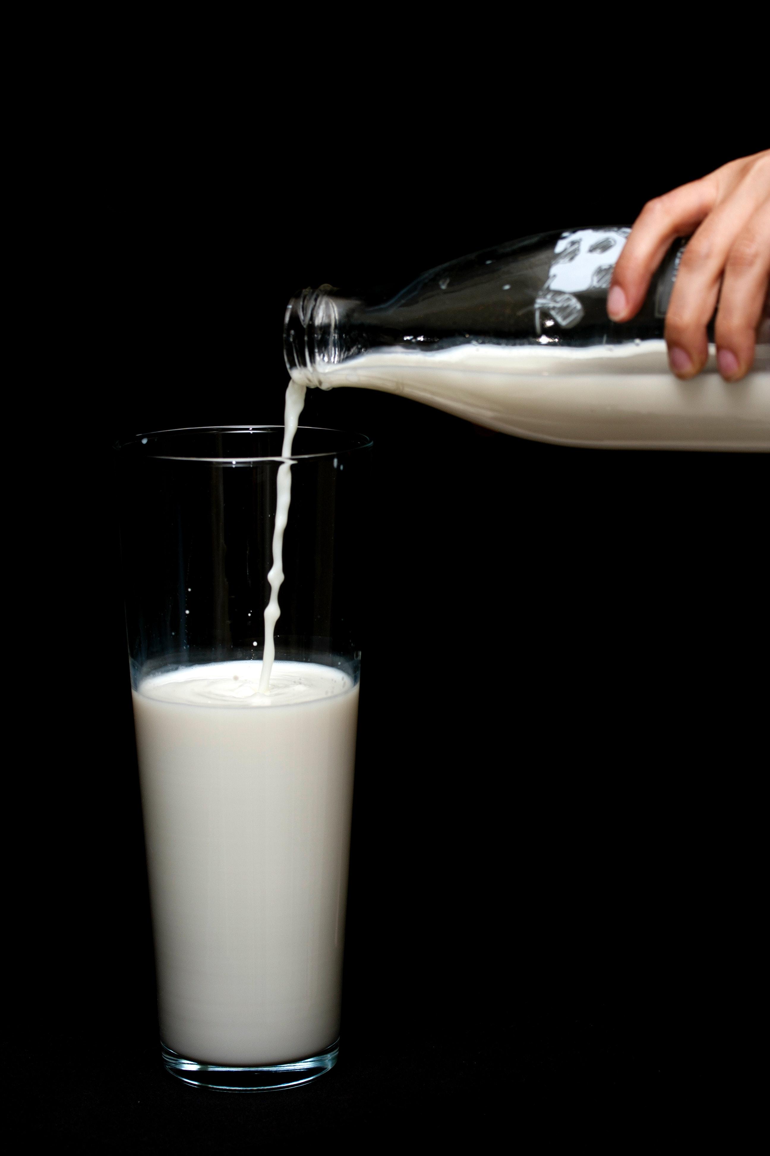 Person Pouring Milk in Highball Glass · Free