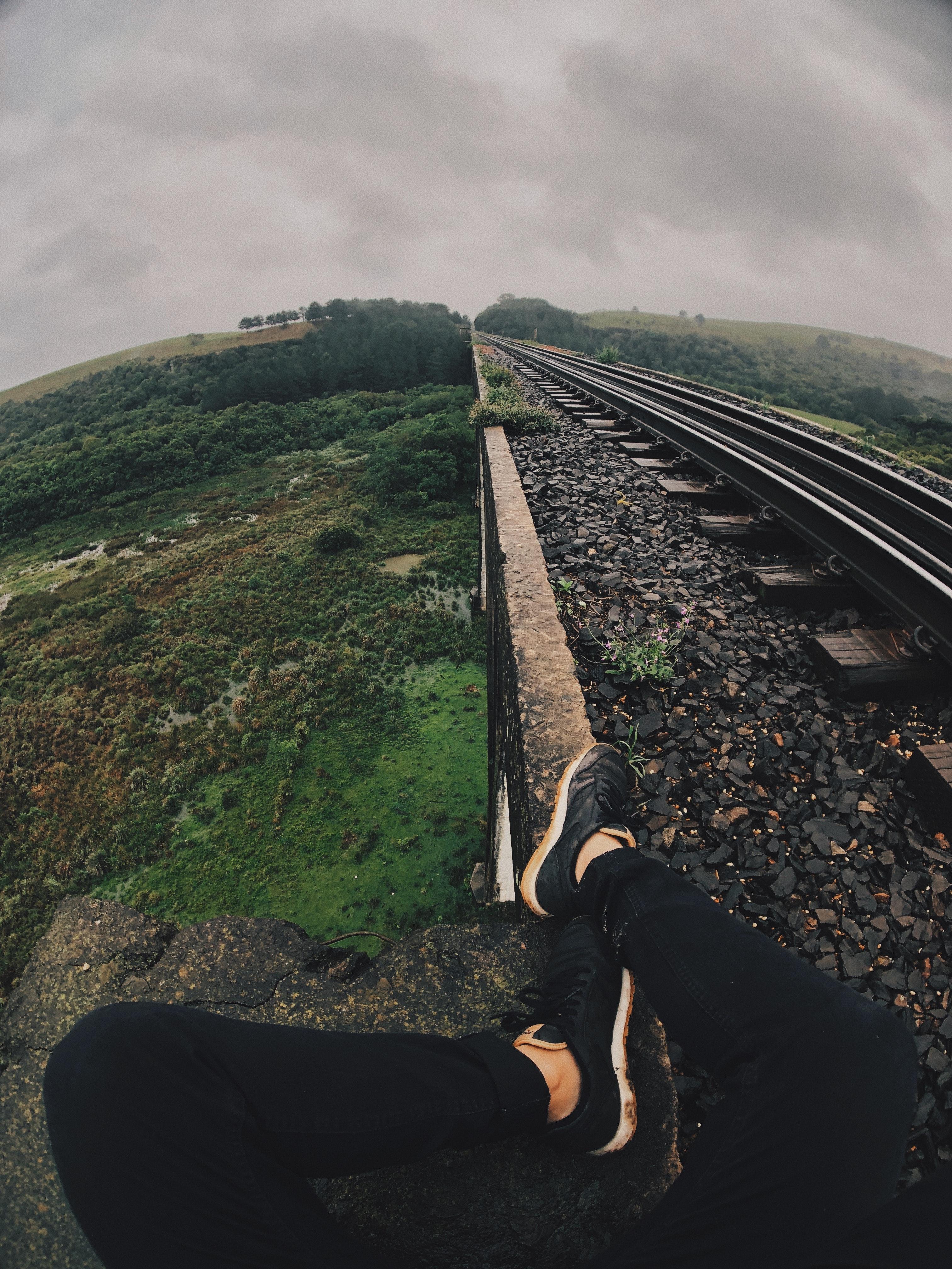 Man Sitting Next to the Railroad Tracks · Free
