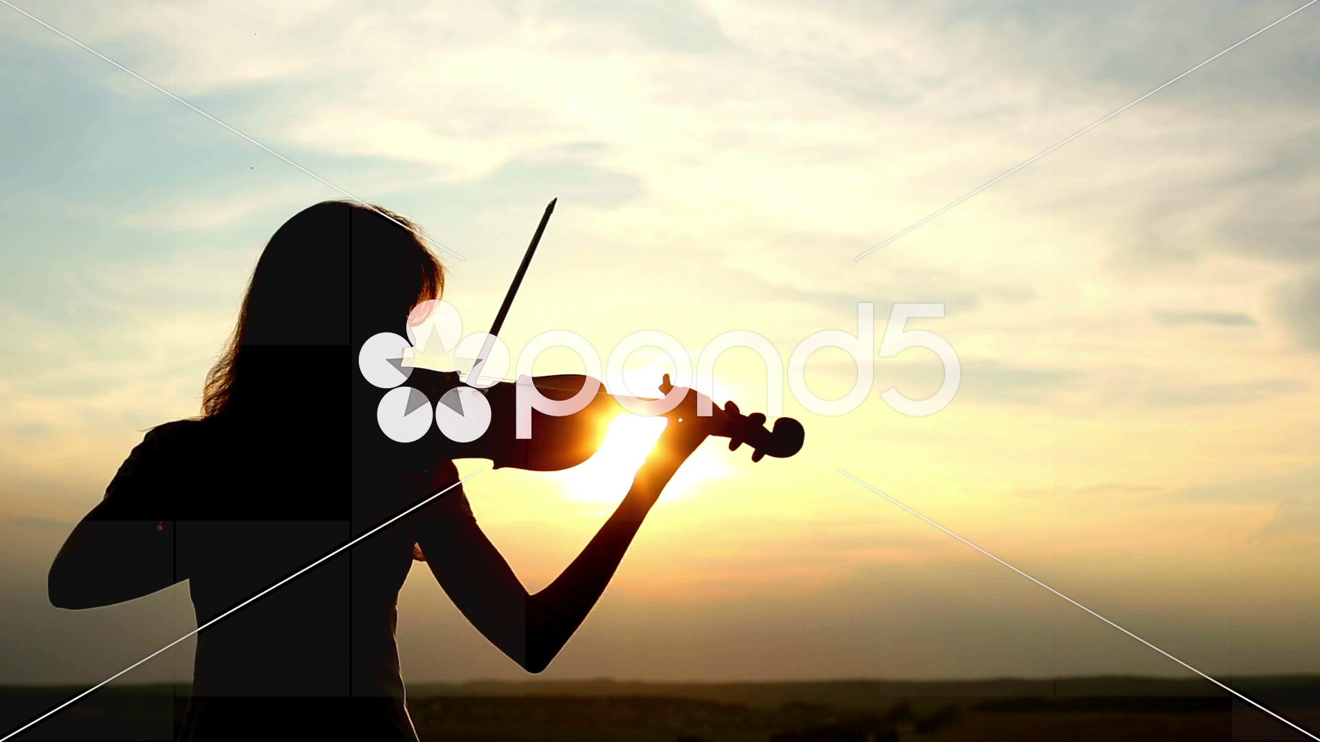Video: Silhouette girl violinist playing the violin at sunset sky