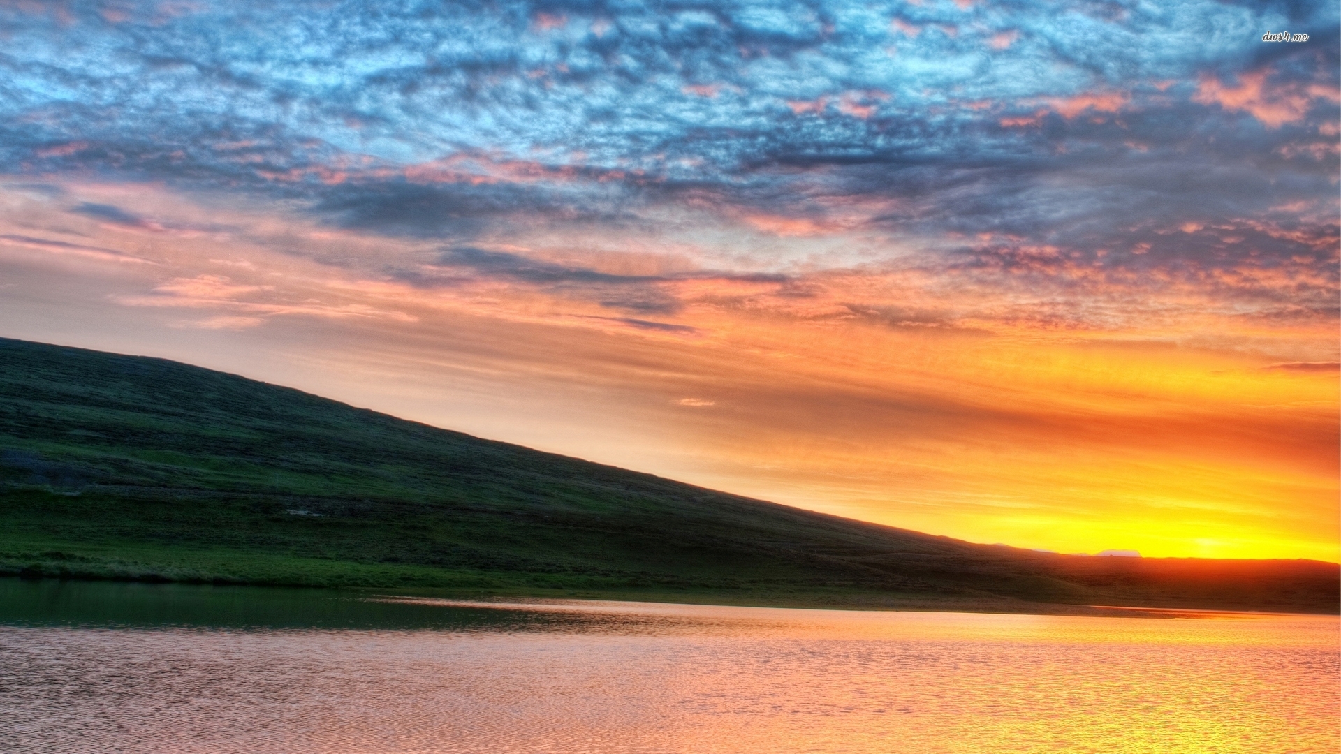 Golden sunrise behind the green hill by the lake wallpaper