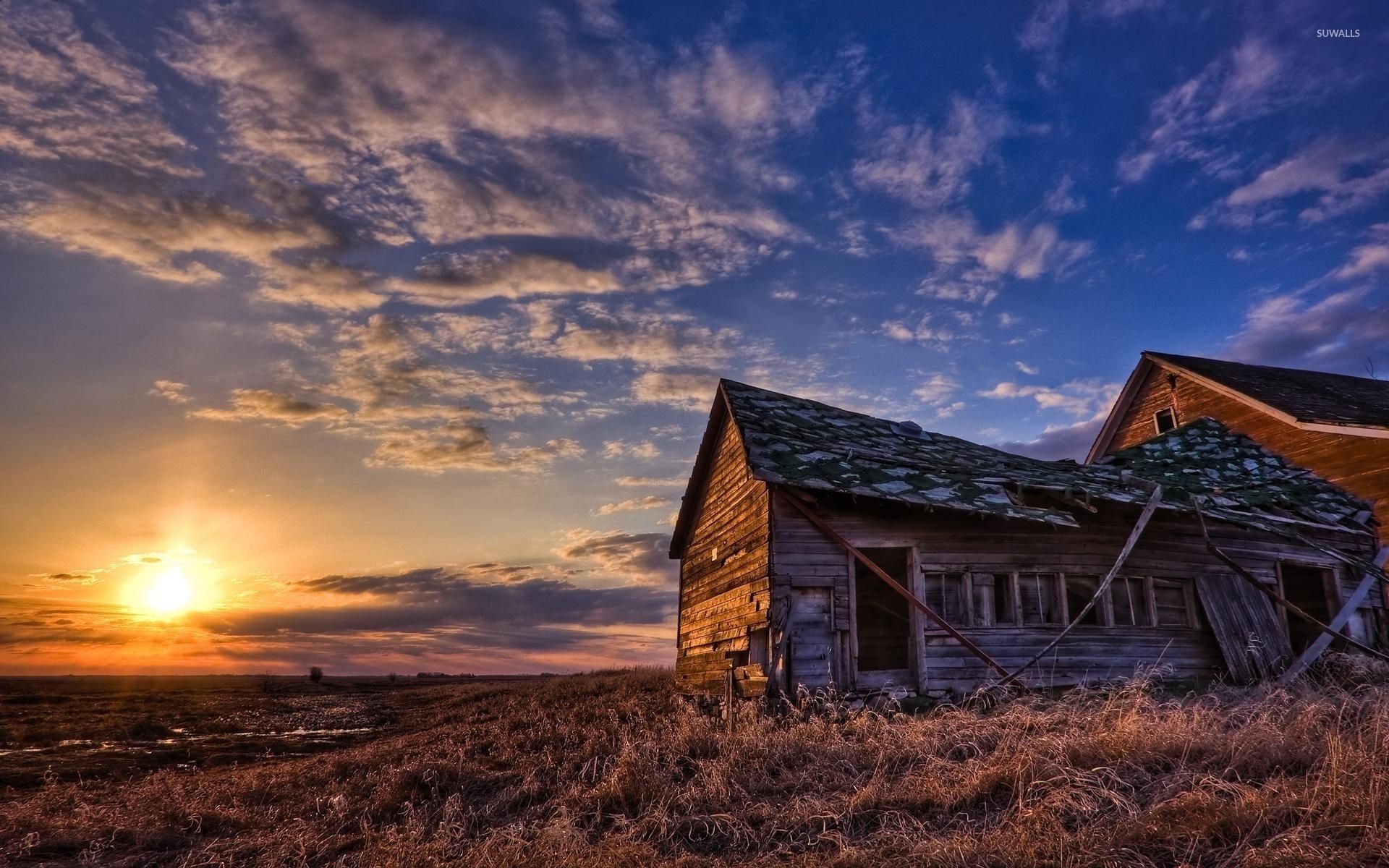 Amazing sunset sky above the forgotten house on the field