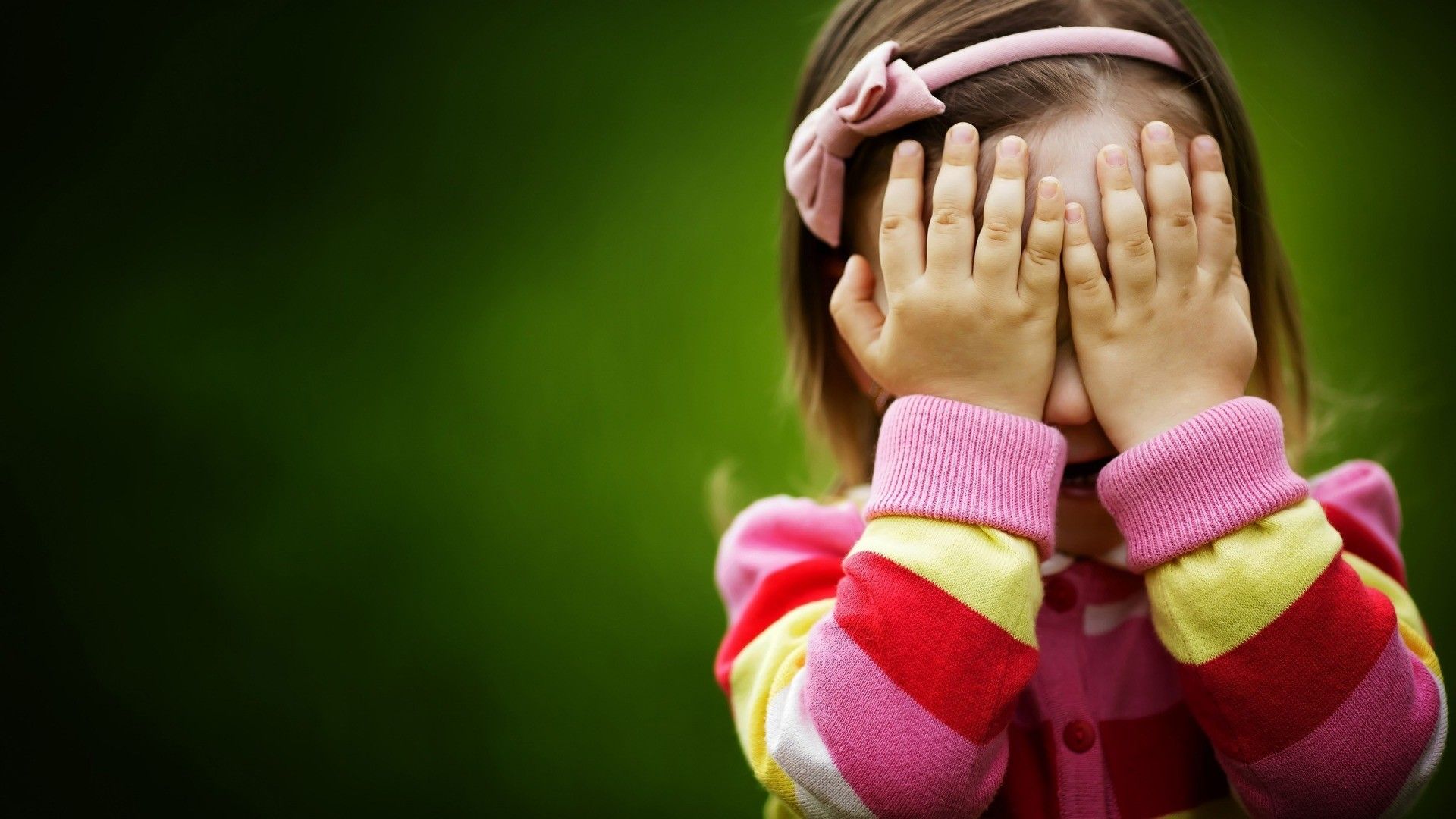 Cute little girl covered her face with her hands wallpaper