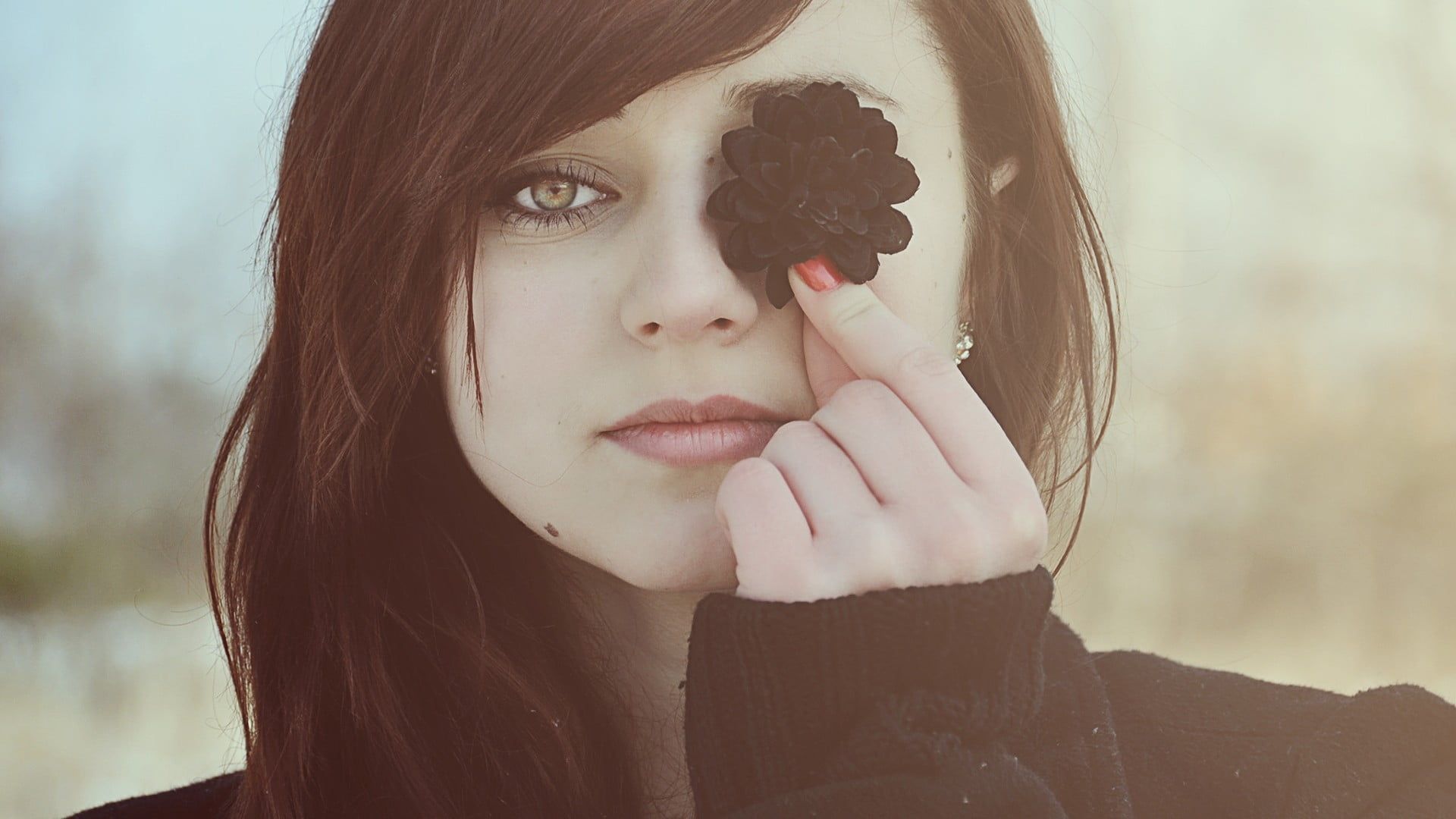 Woman wearing black sweater covers her eye with a black flower HD