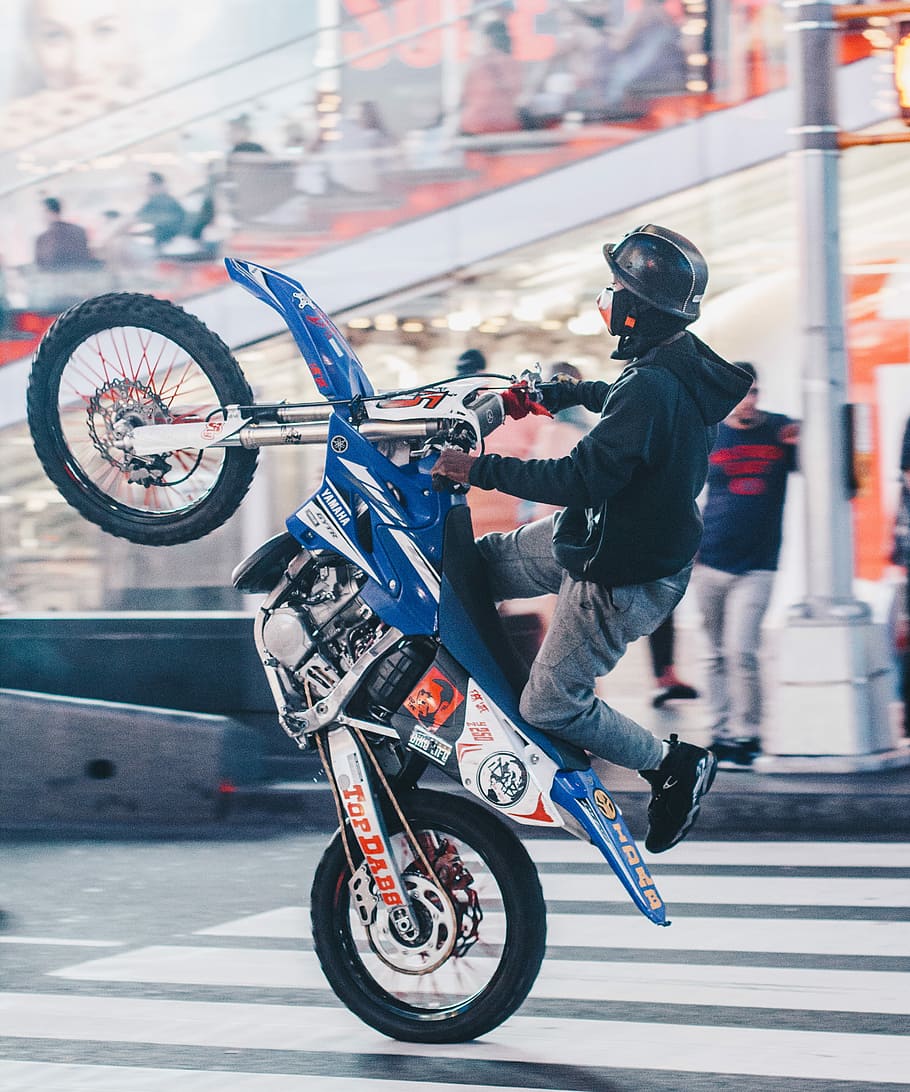 HD wallpaper: selective focus photography of man doing wheelie on motocross dirt bike, man riding blue and white Yamaha dirt bike