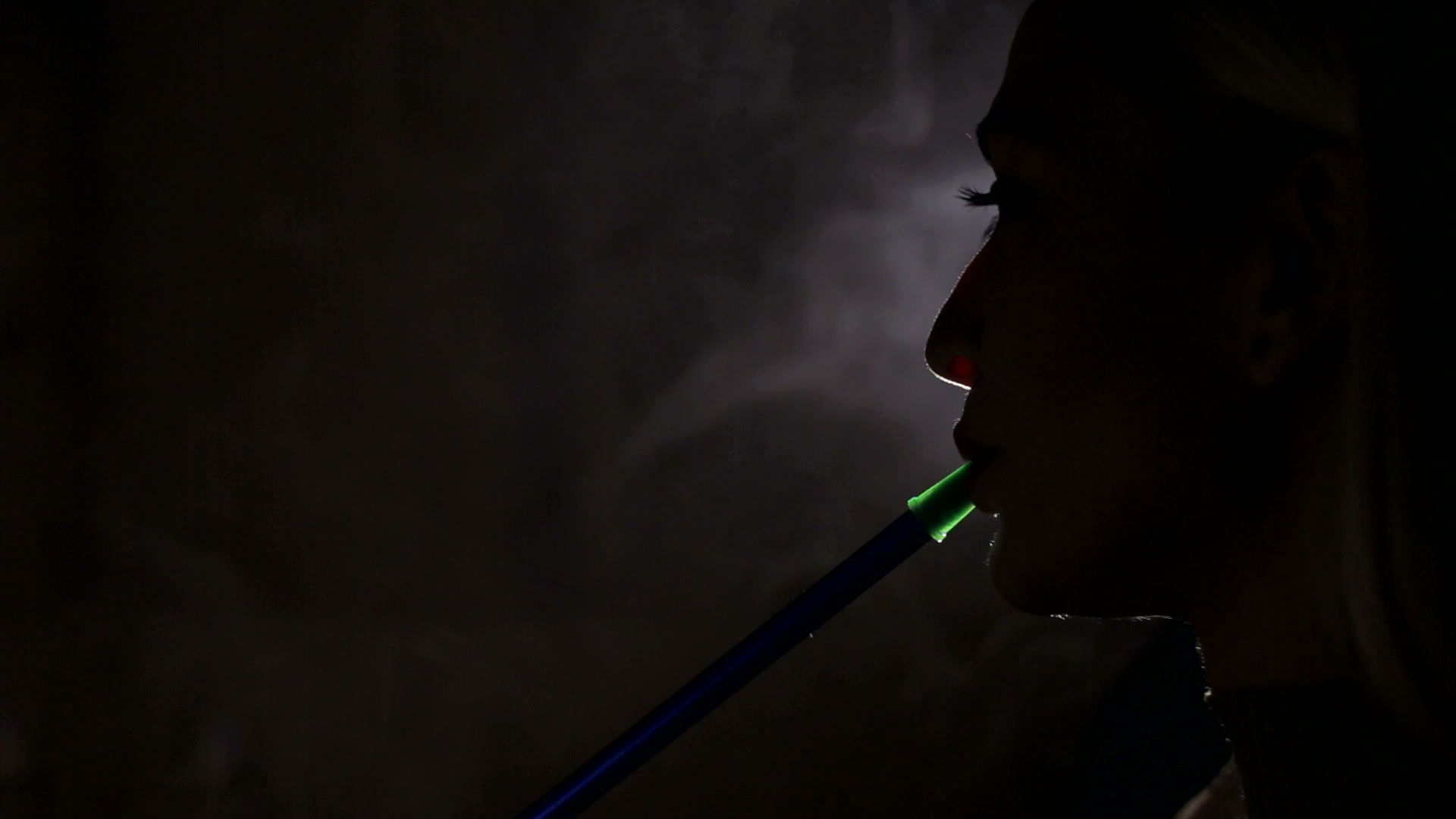 Silhouette of a girl Smoking a hookah on a black background