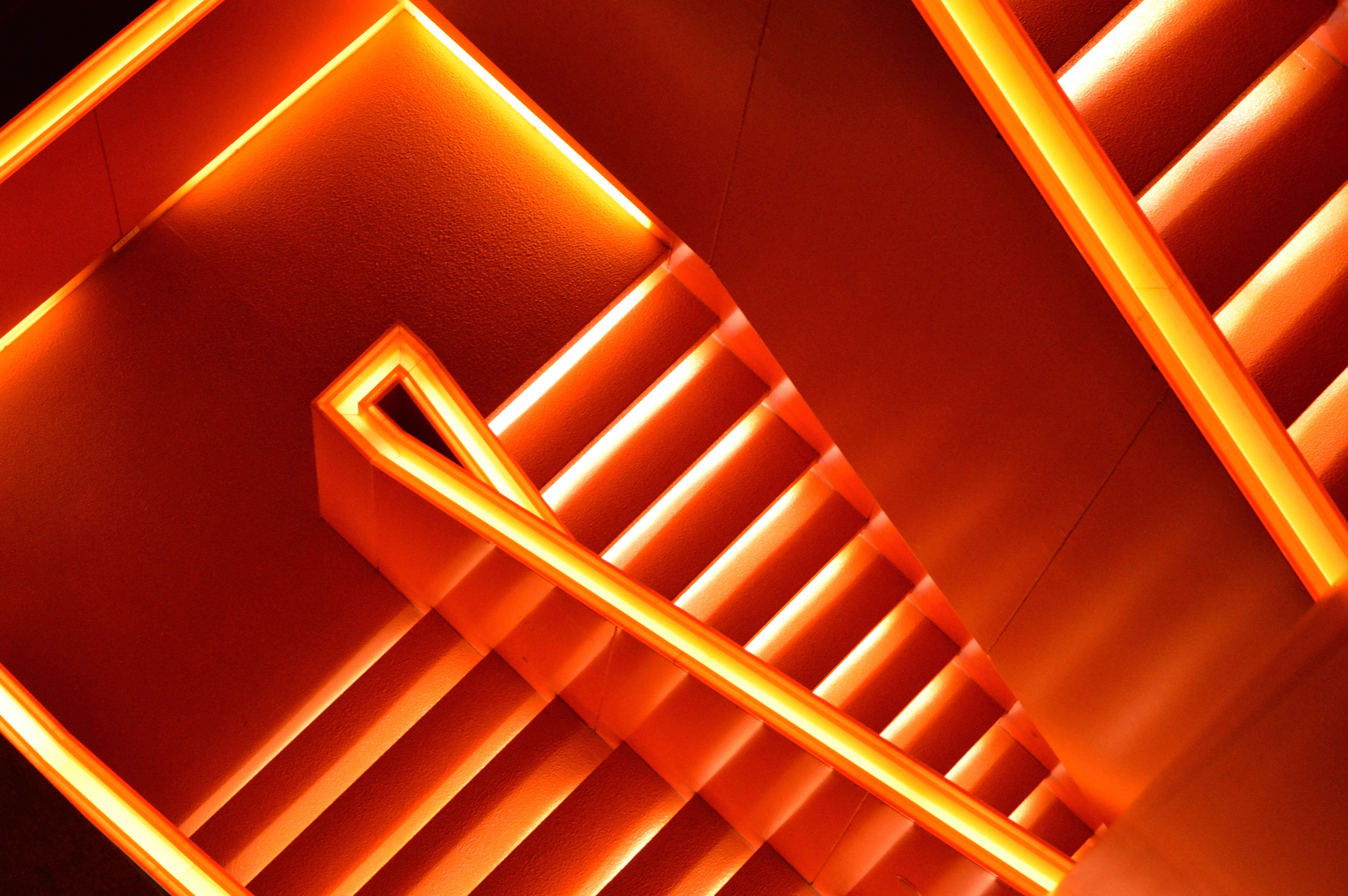 A stairway illuminated by bright orange neons. Tape lights