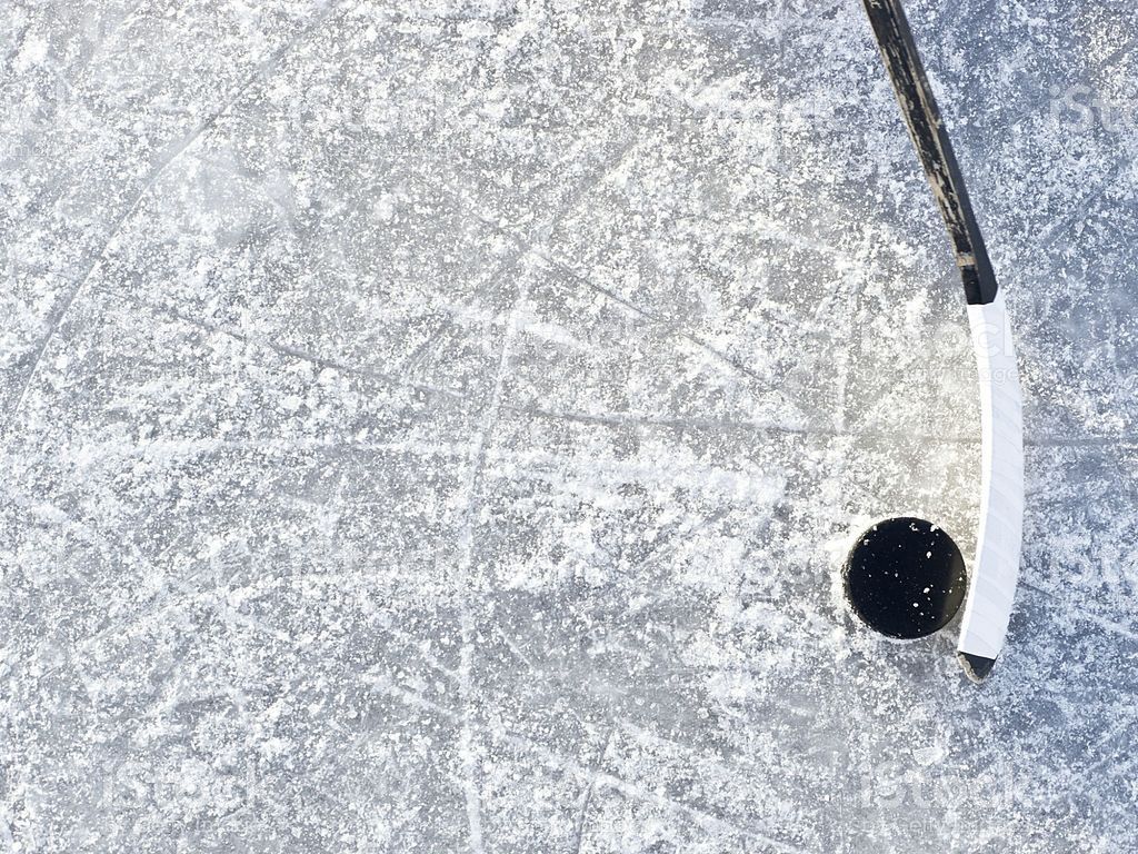 Ice hockey background with stick, puck, and ice with snow on it at