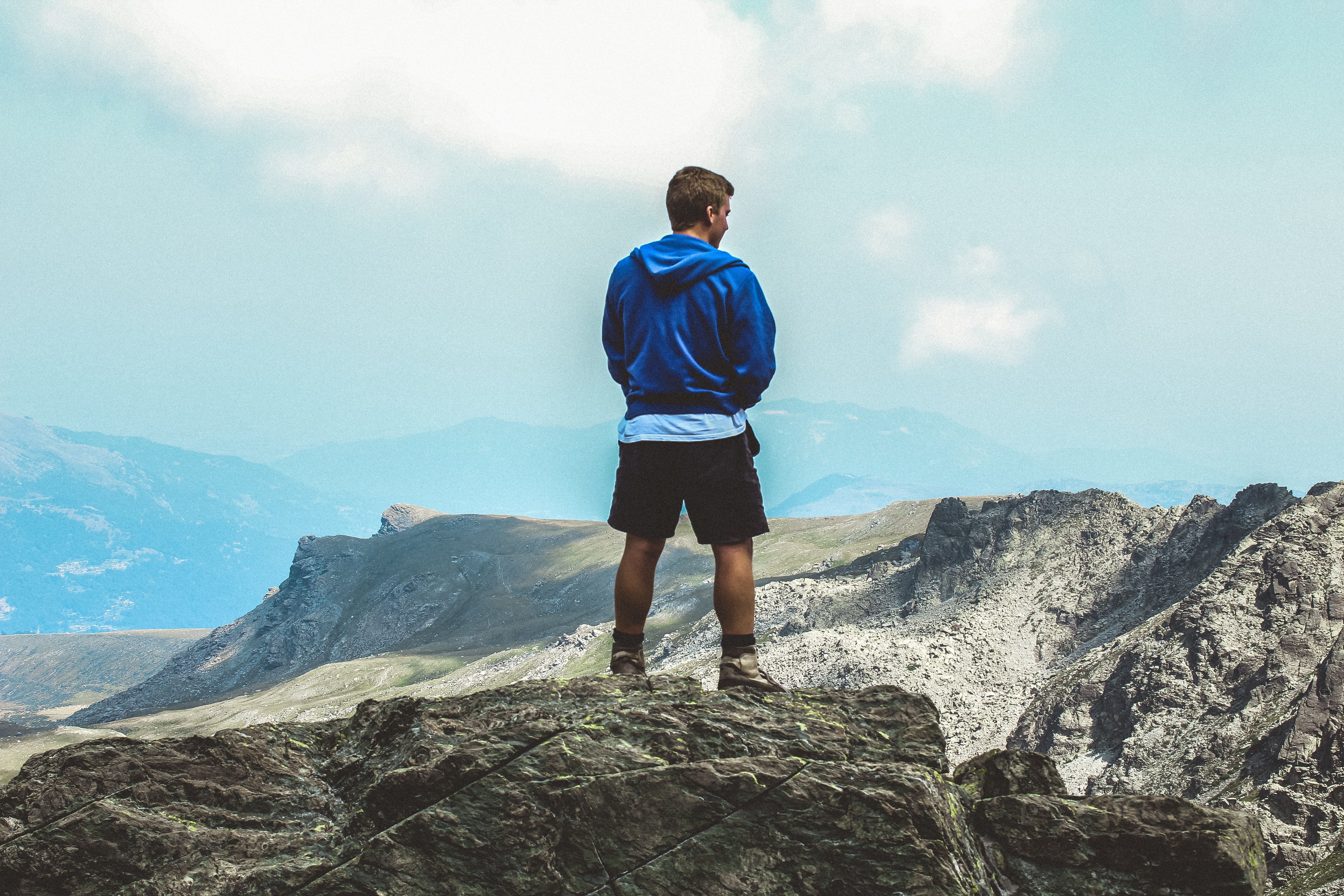 Man Wearing Blue Hoodie Standing on Top of Mountain · Free