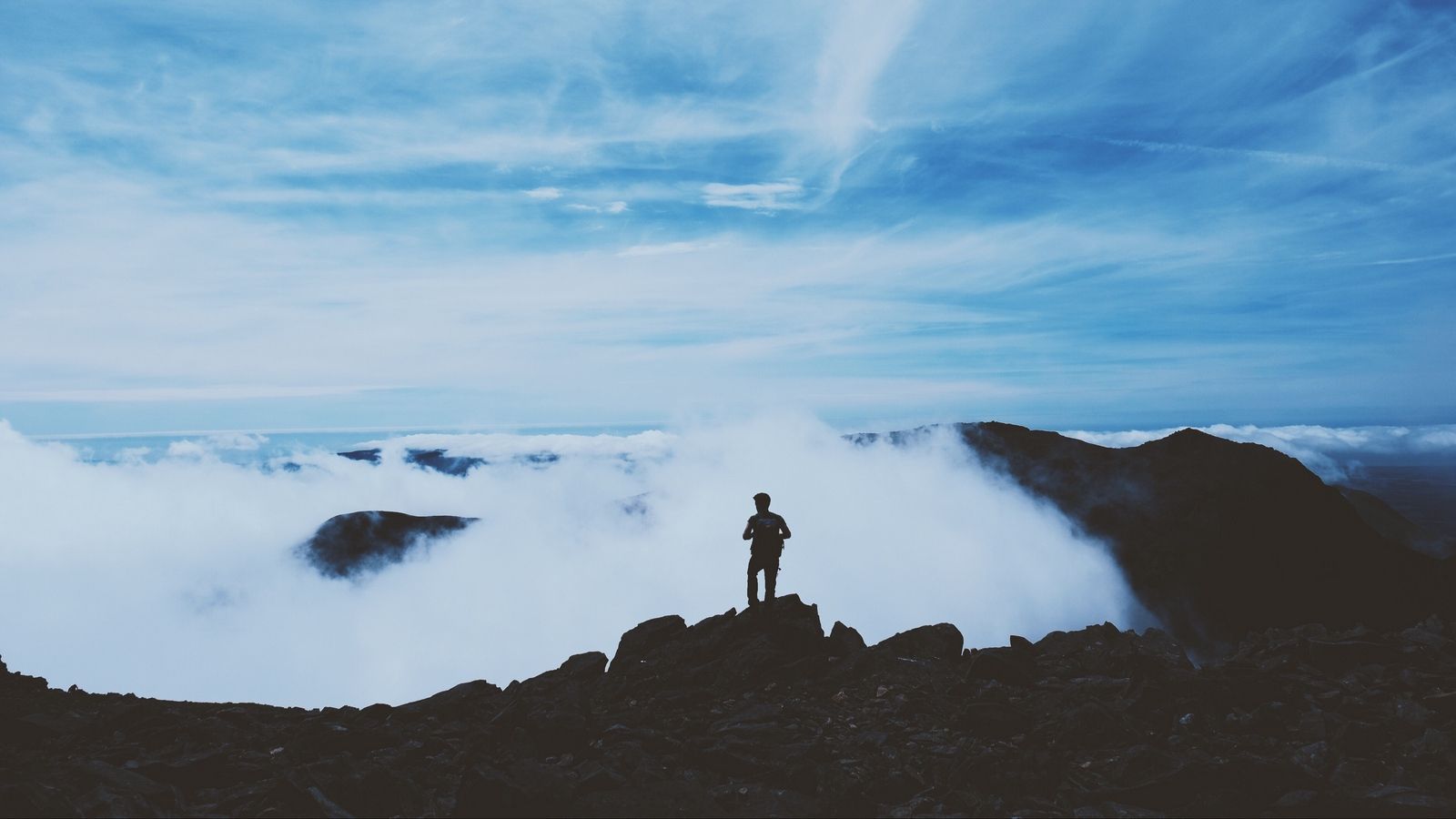 Download wallpaper 1600x900 man, silhouette, mountains, clouds