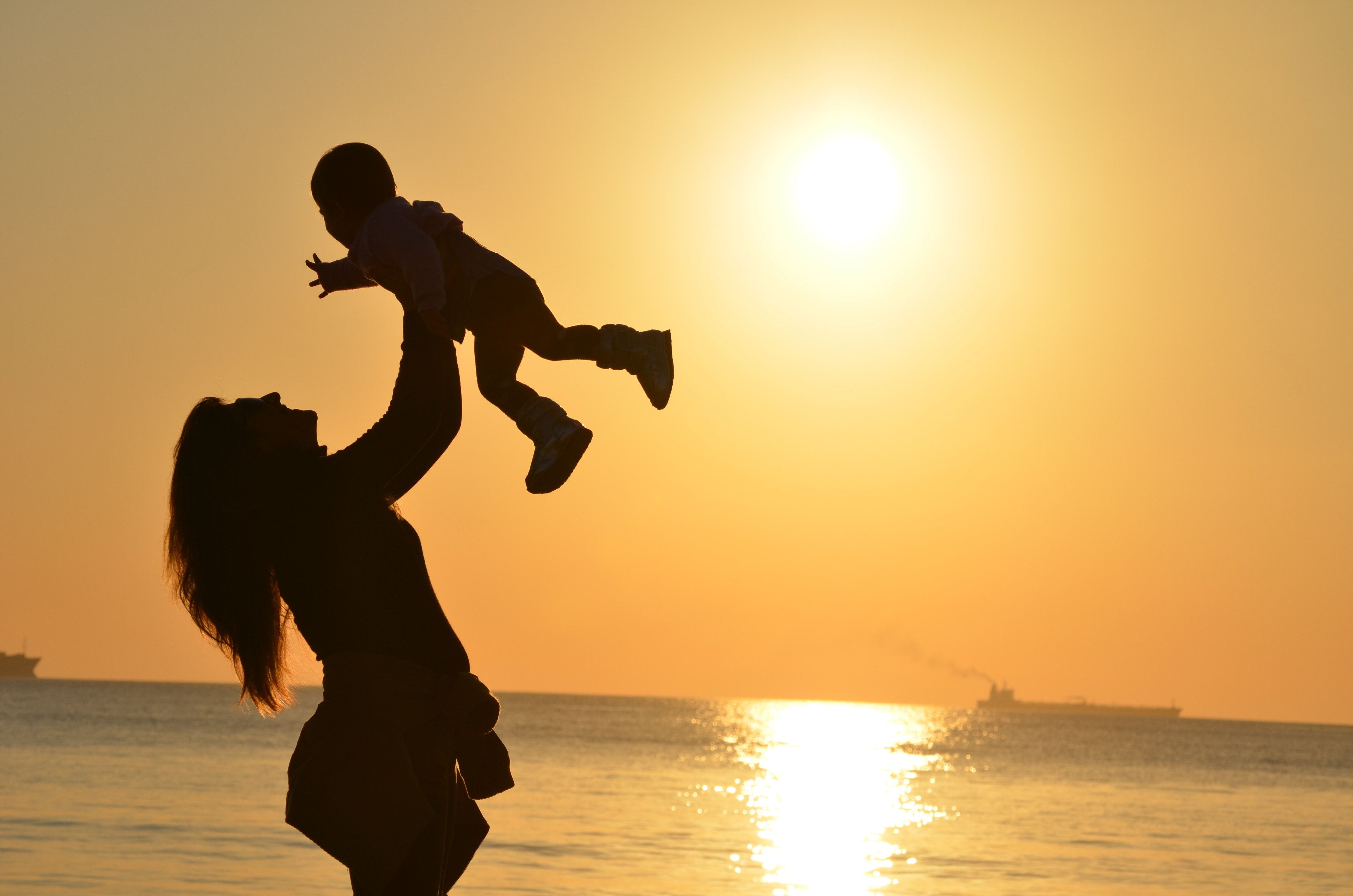 Woman Carrying Baby at Beach during Sunset · Free