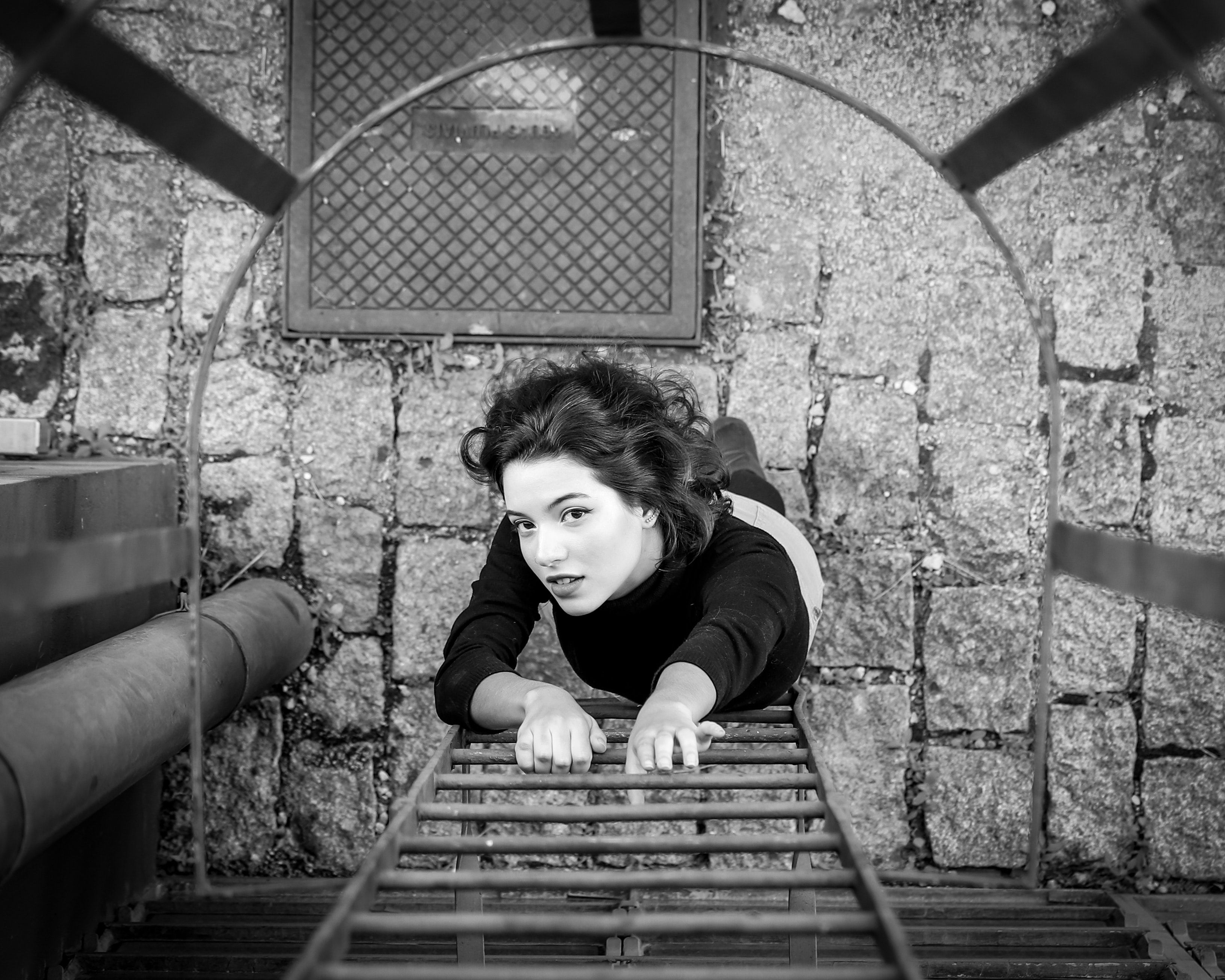 Gray scale photo of a woman about to climb the fire escape ladder