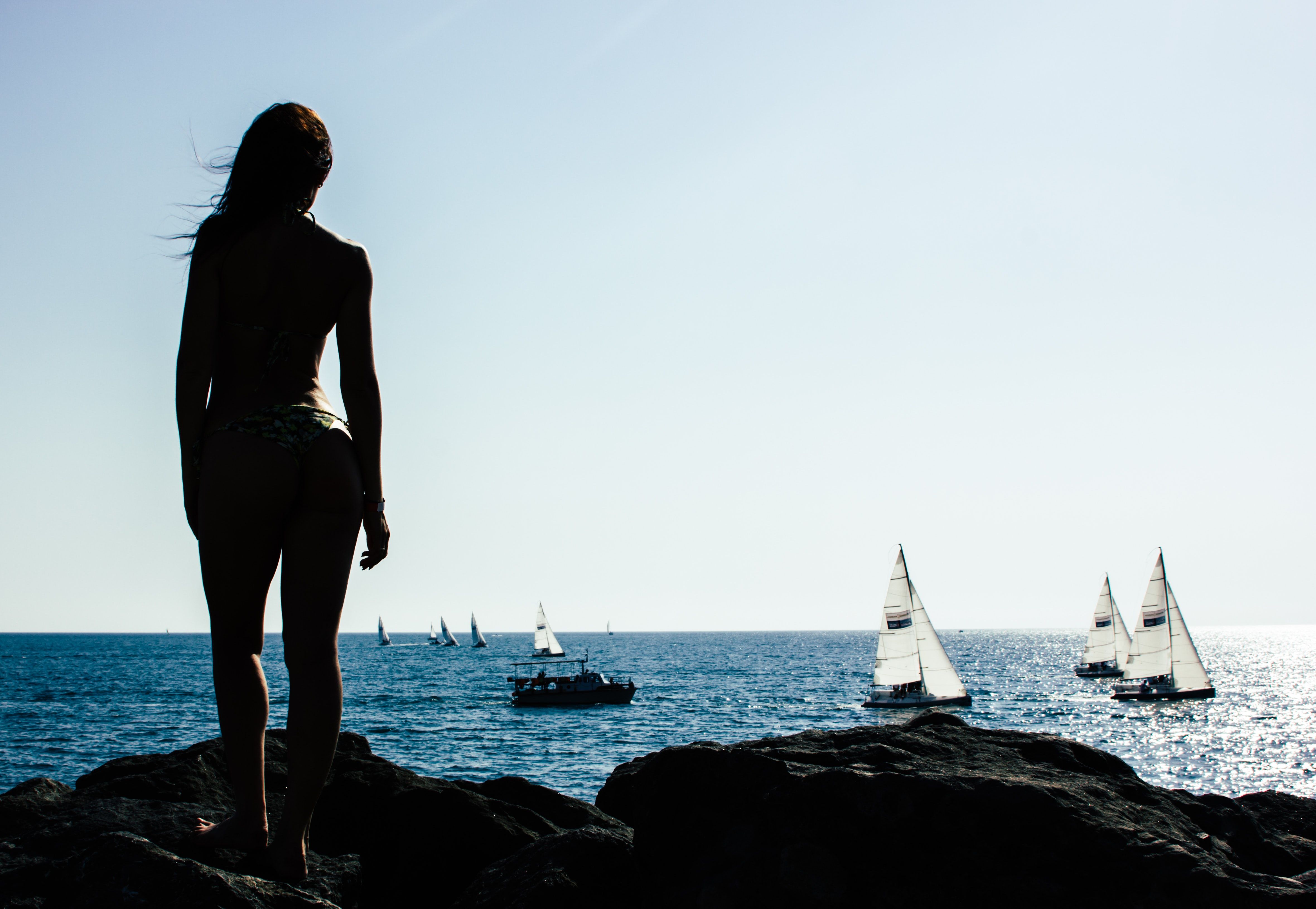 Woman Standing on Rock With Sailing Boats on Sea · Free