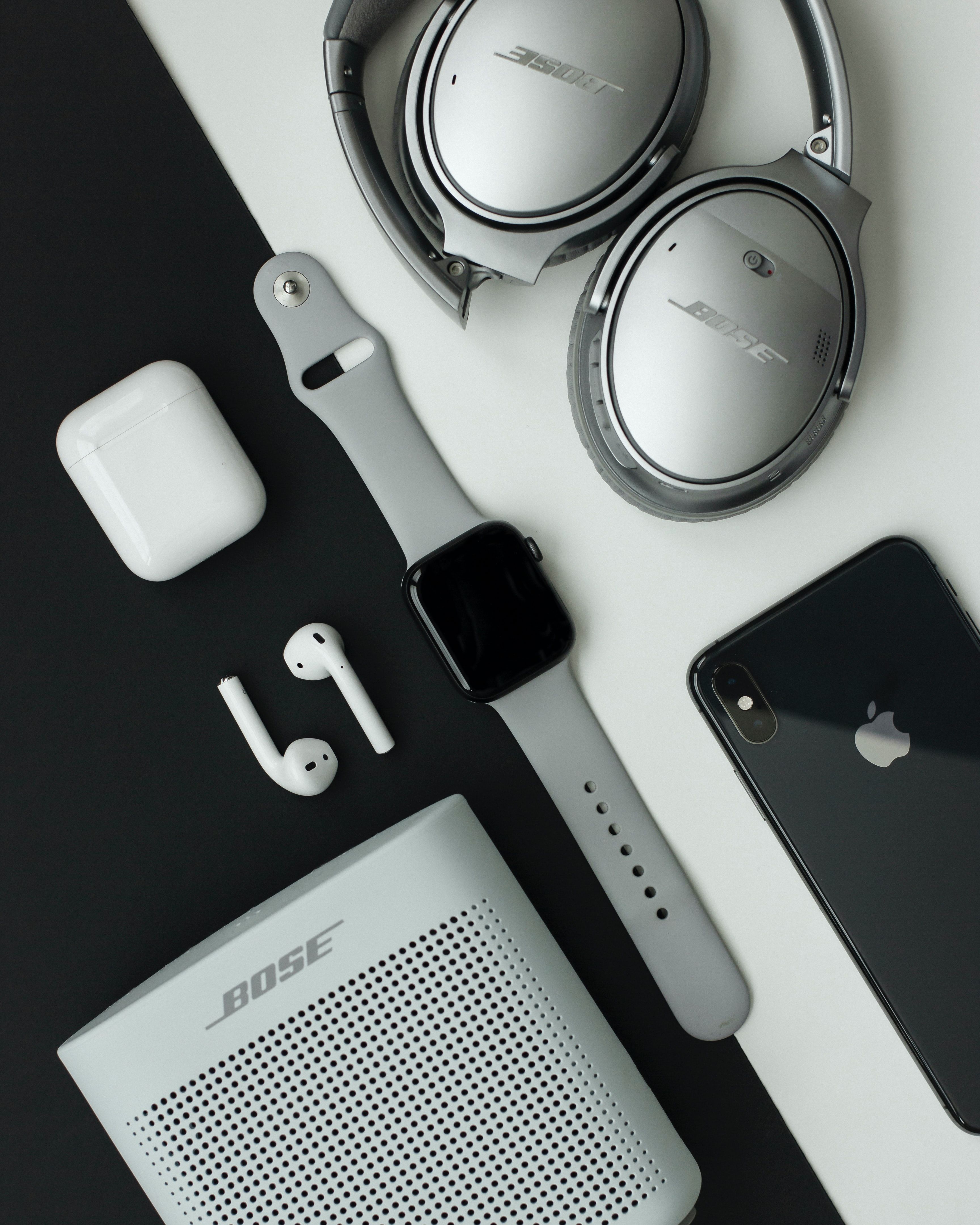 gray Bose headphones, Apple Watch and iPhone on white and black