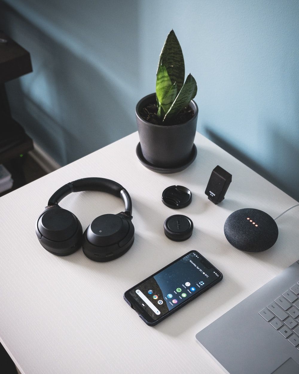 smartphone beside headphones and Google Home Mini photo