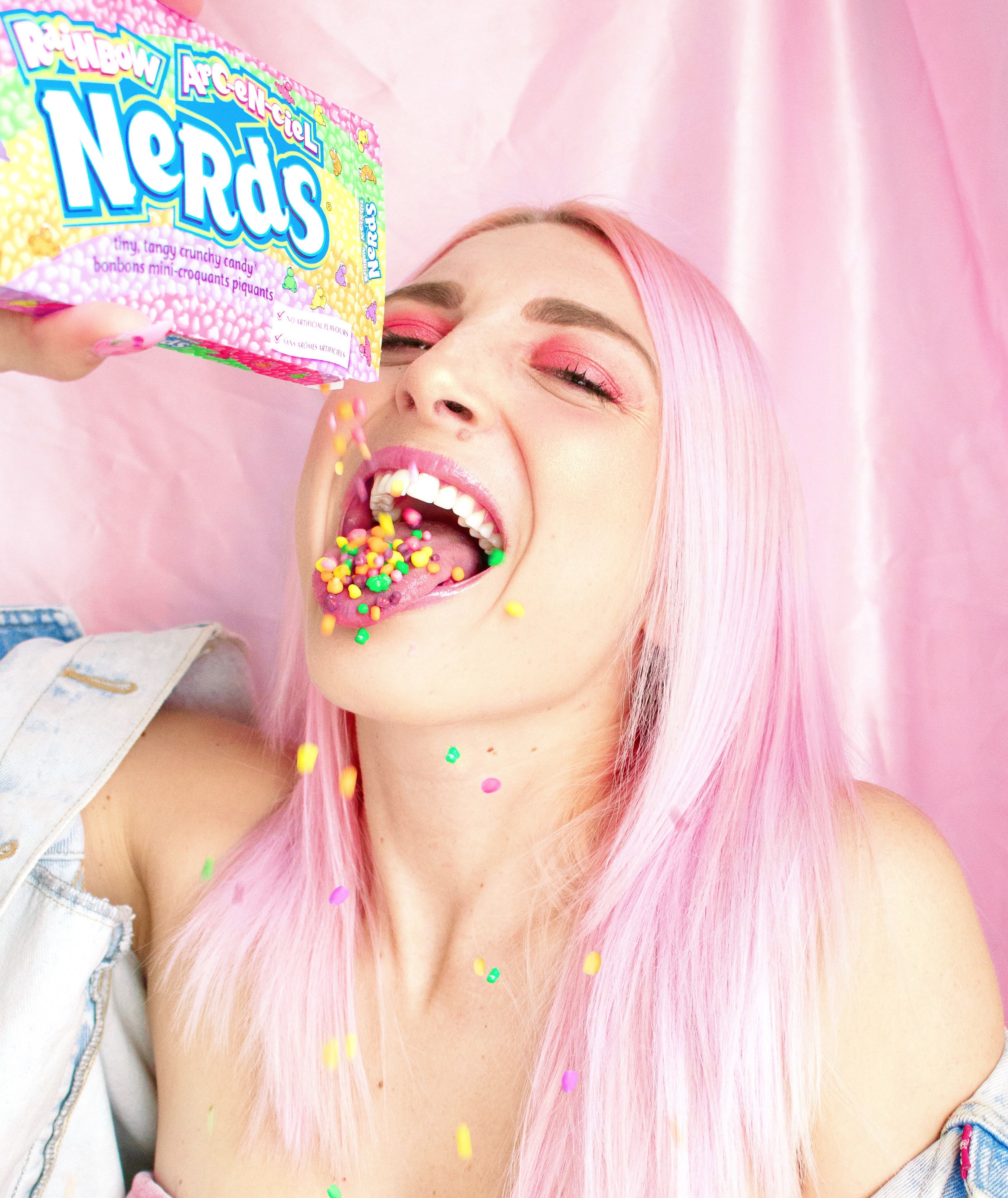 Woman With Pink Hair Pouring Nerds Candy in Her Mouth · Free Stock