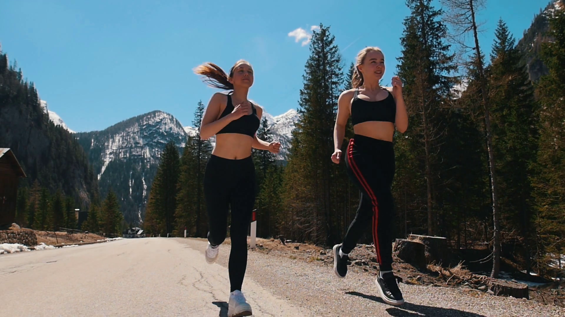 Two young sportive women in sports bra jogging on the road