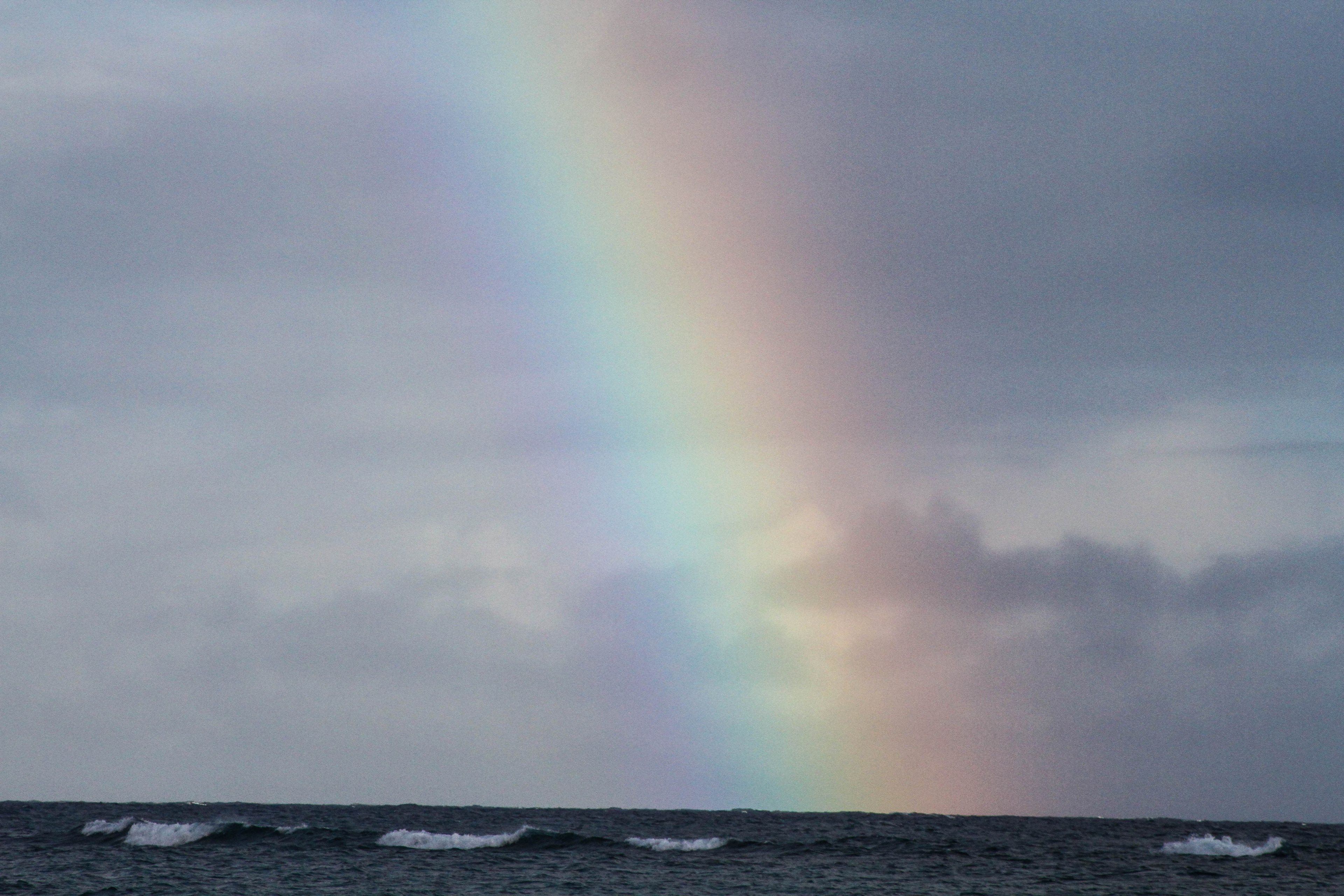 a rainbow shining through a cloudy sky rainbow through clouds 4k
