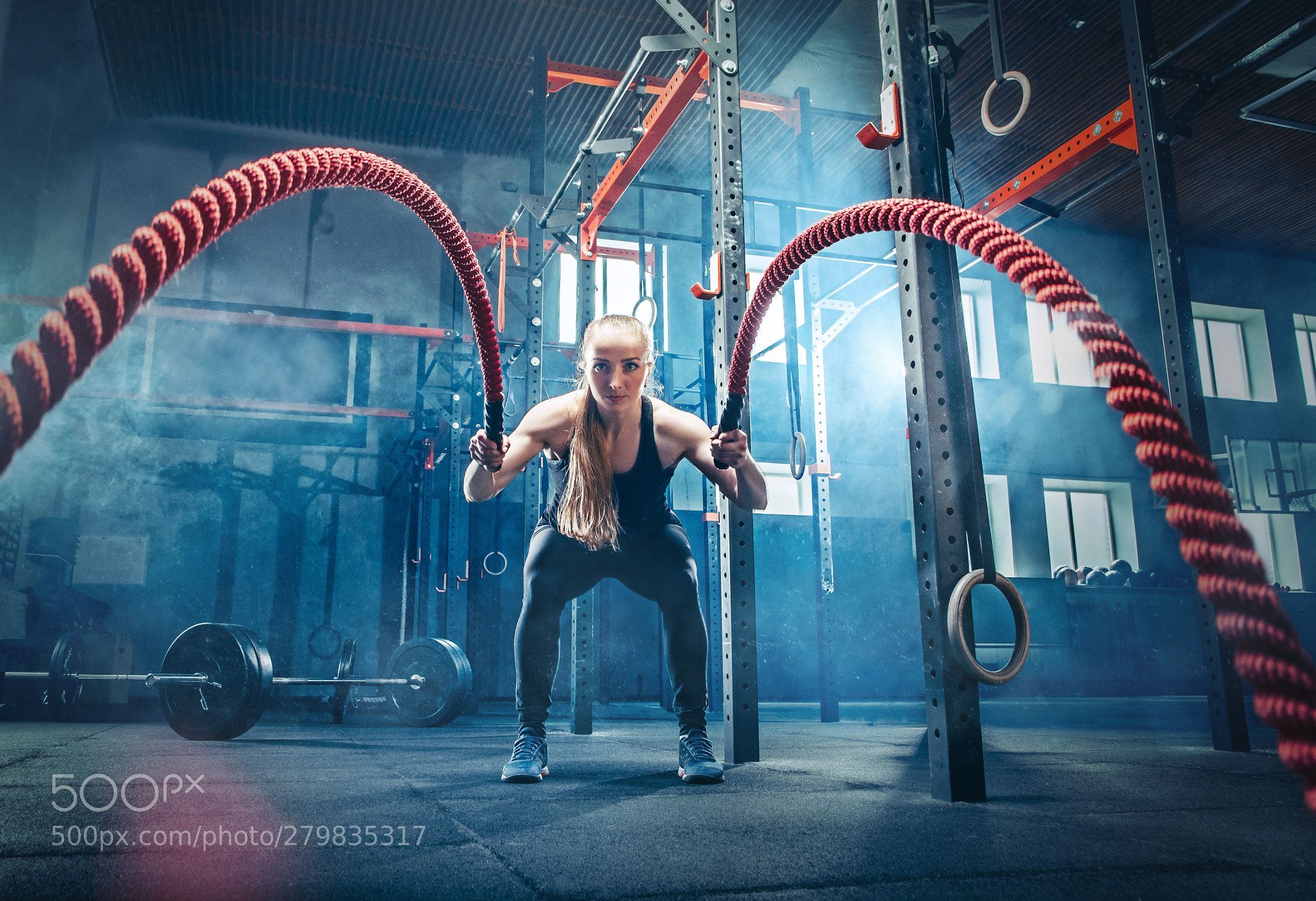Woman with battle ropes exercise in the fitness gym. Woman