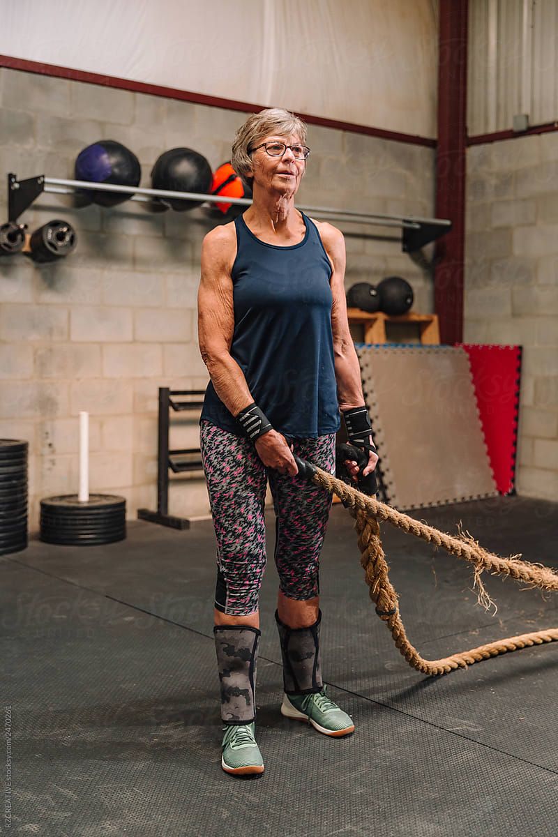 A fit mature woman in her seventies standing in a gym holding