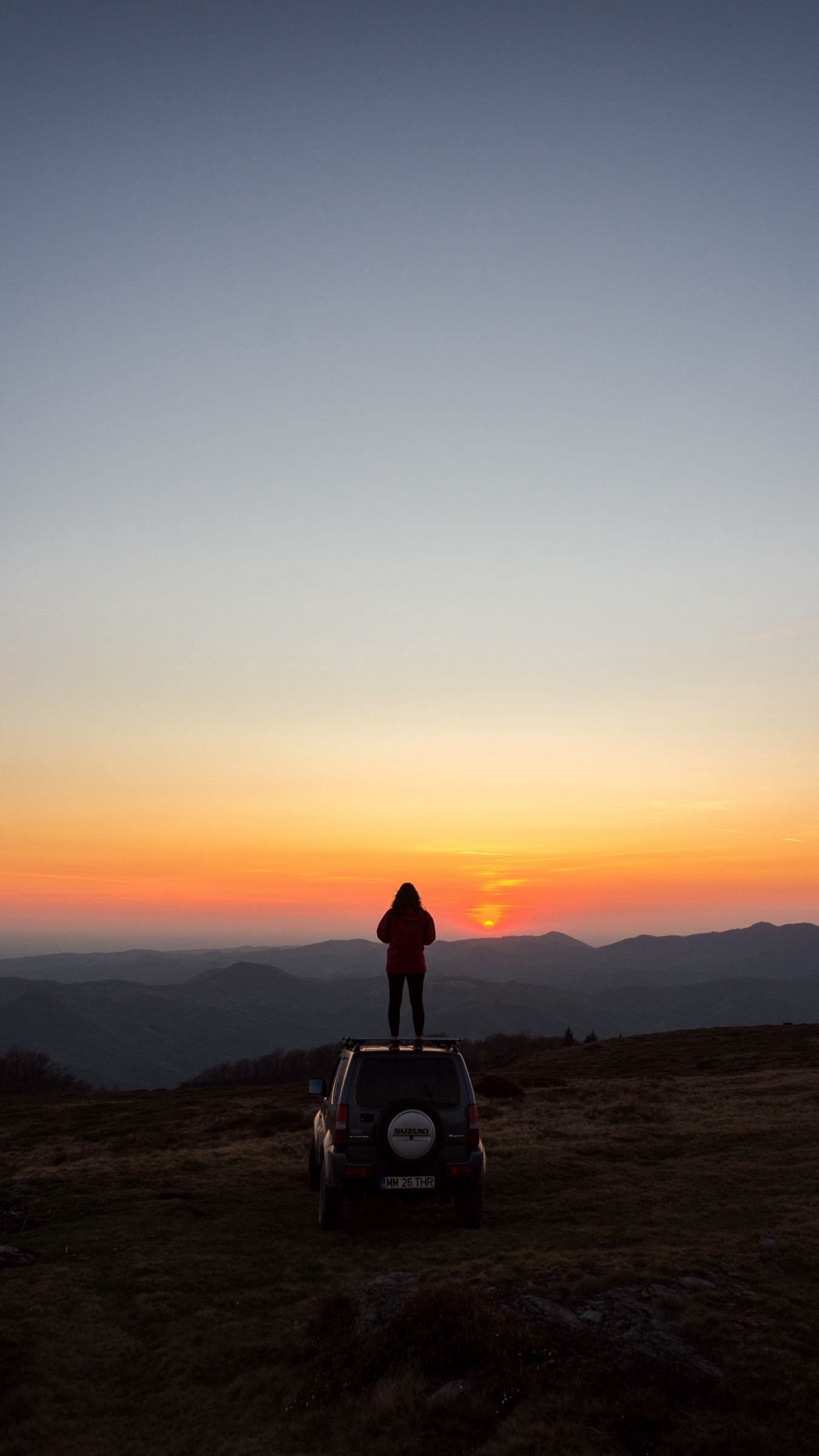 Download wallpaper 1350x2400 car, person, sunset, mountains