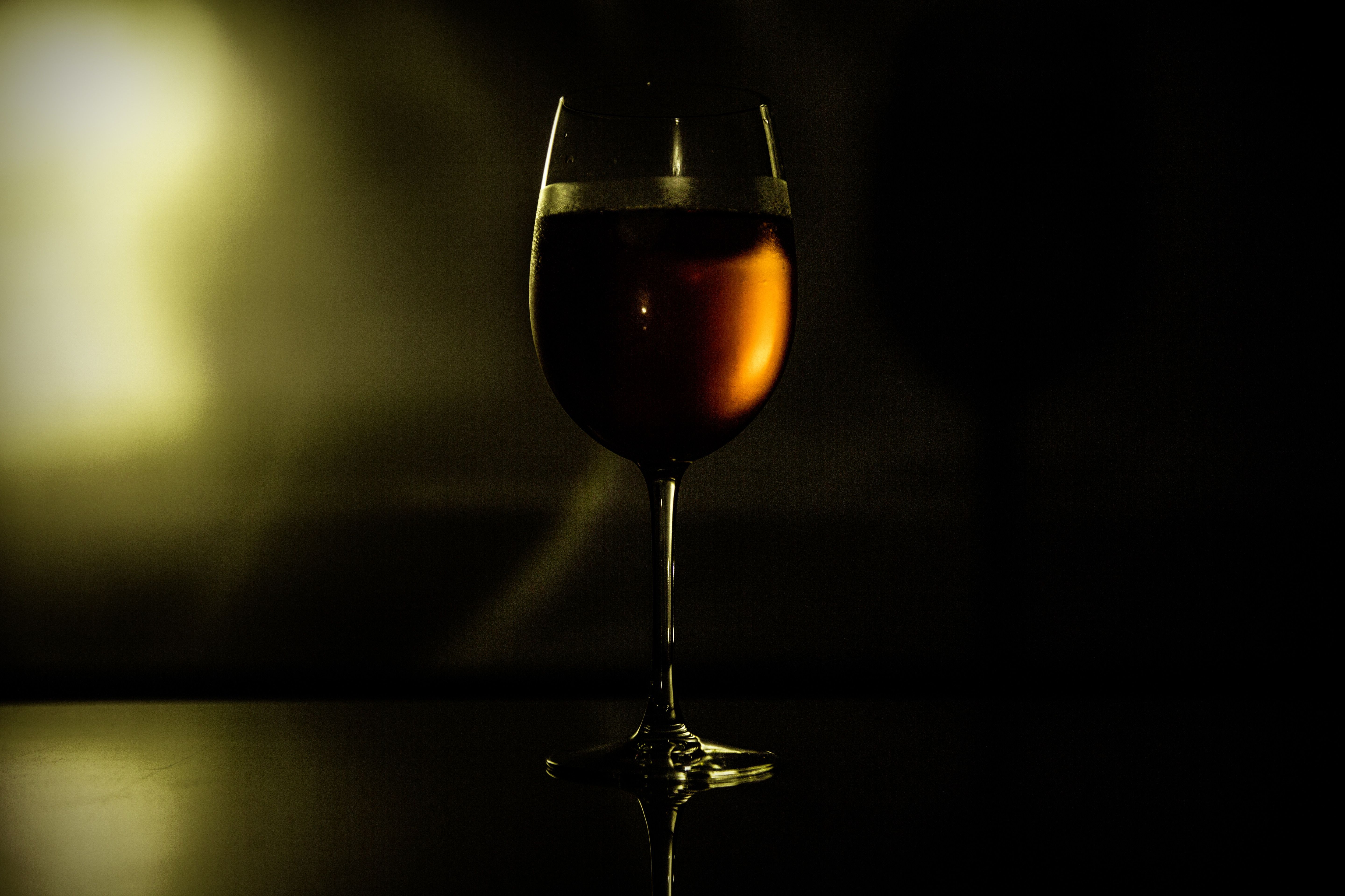 clear wine glass pouring liquor in dark room free image